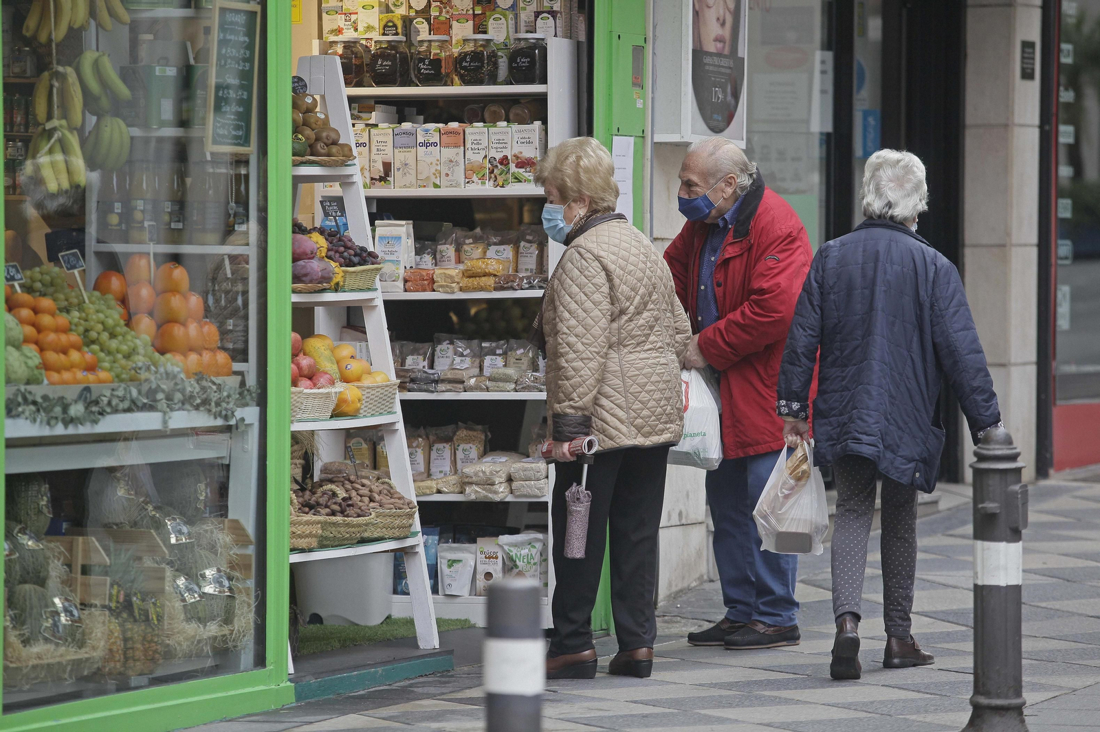Dos personas aguardan para comprar en una frutería del centro de Algeciras.