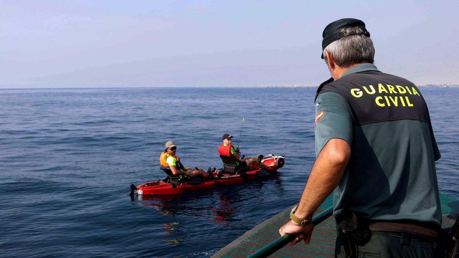 Un agente solicita su documentación a pescadores en kayak.