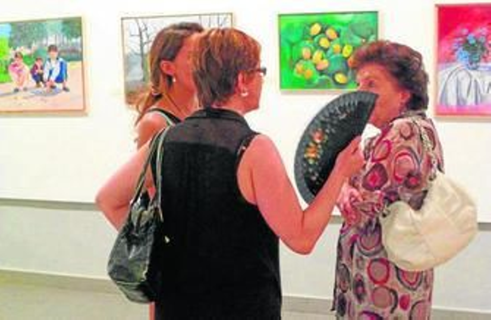 Un grupo de mujeres, ante algunos de los cuadros.