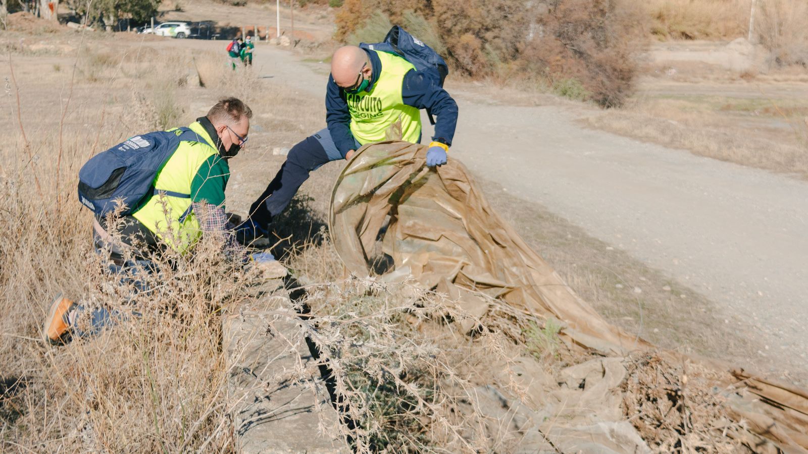 Dos participantes retirando un plástico de invernadero