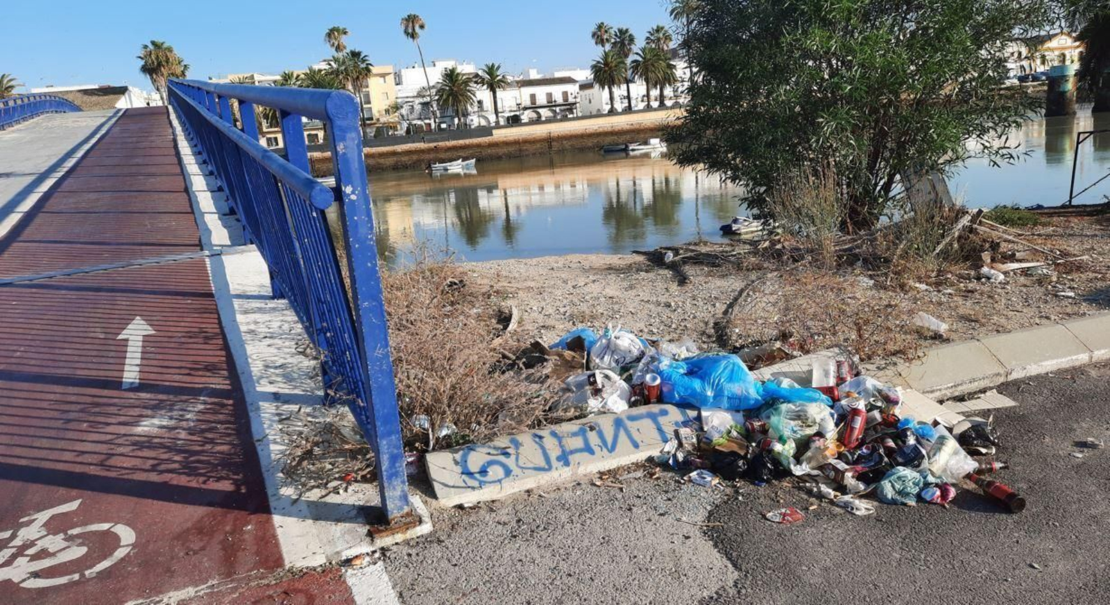 Un montón de basura junto a la pasarela sobre el río Guadalete.