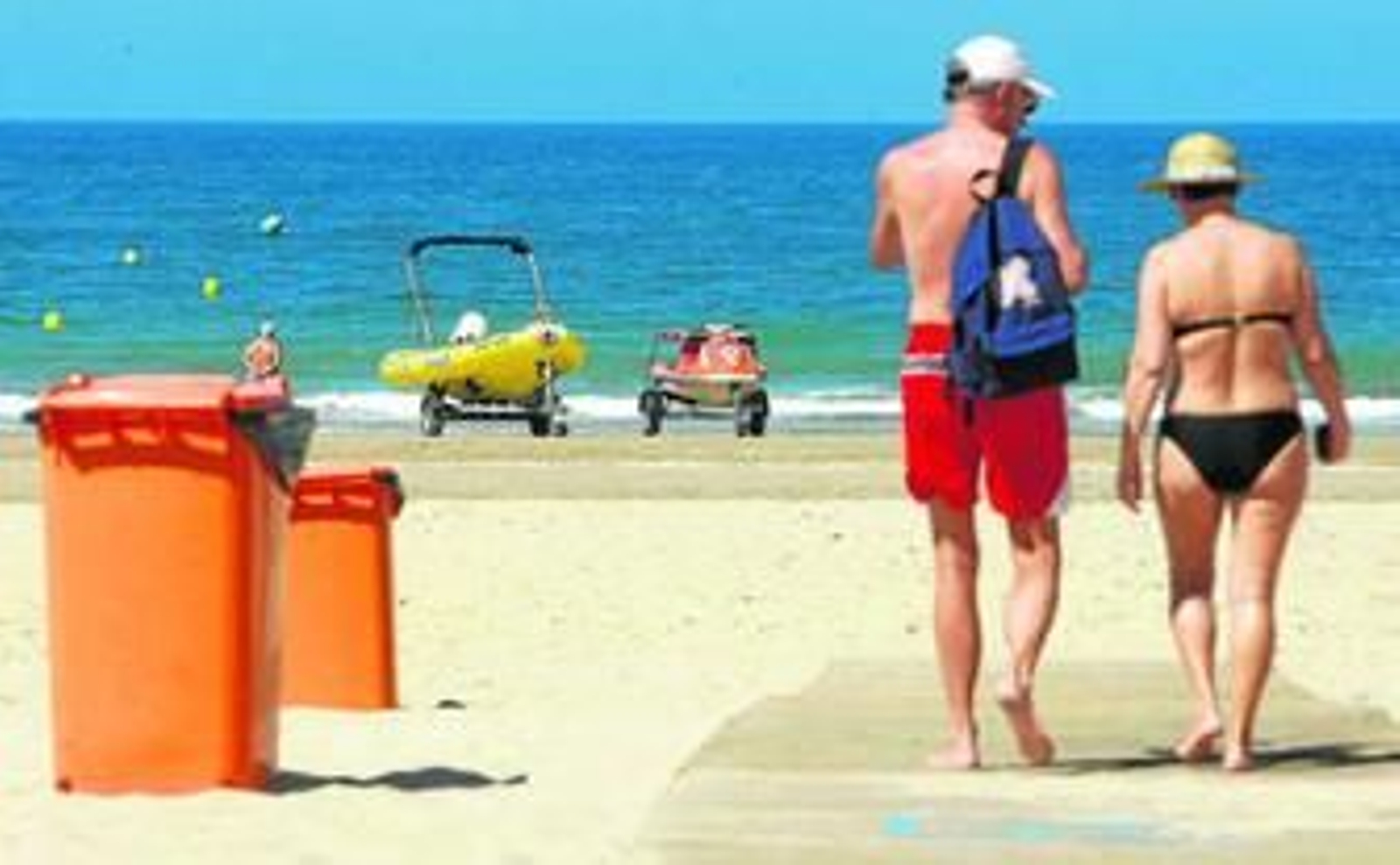 Dos personas llegan a la playa de la Victoria ante la preparación del dispositivo playero.