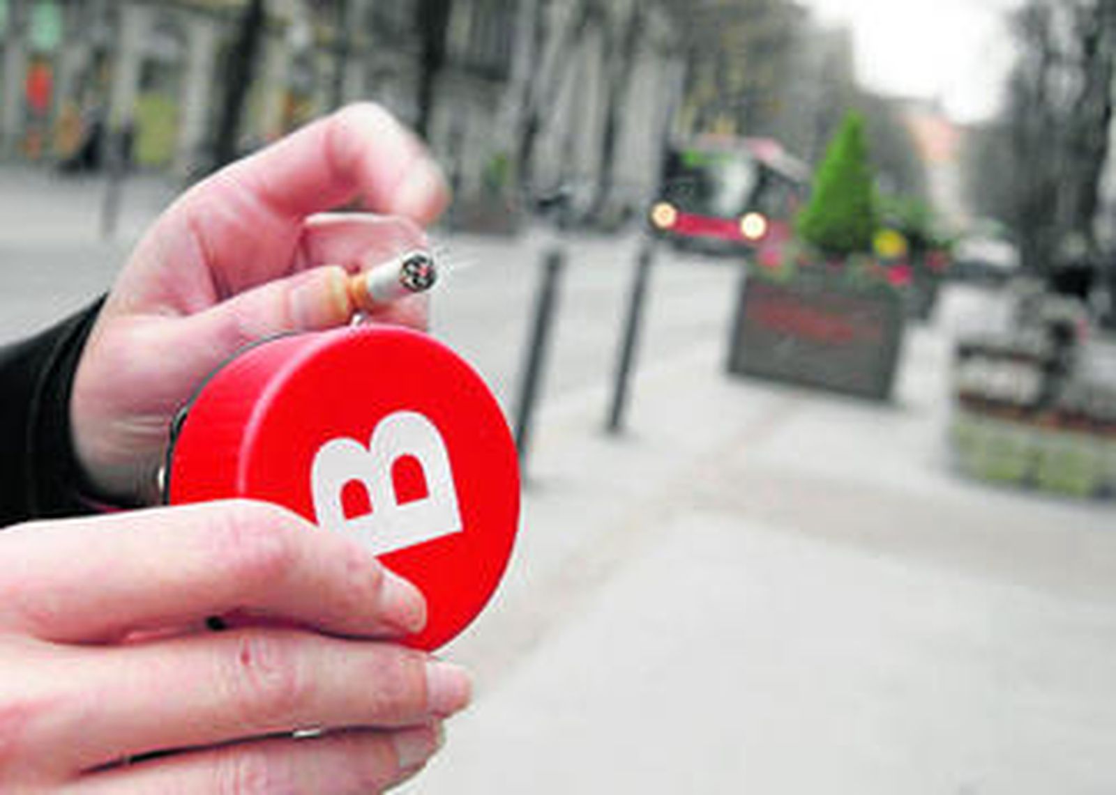 Un fumador utiliza un cenicero portátil en la calle de una ciudad española.