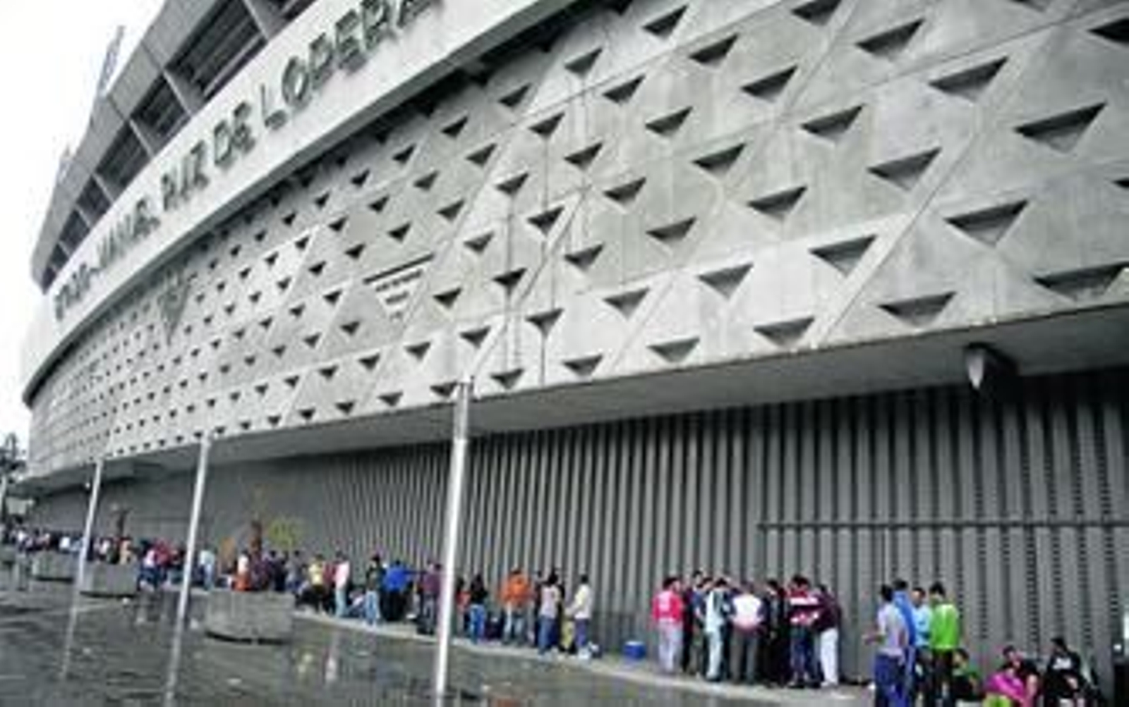 Aficionados béticos guardan la cola por la mañana protegidos de la lluvia.