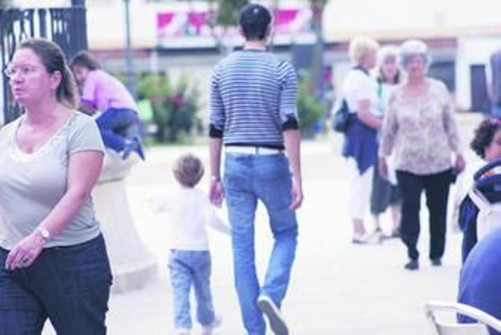 Un joven veinteañero camina en el Paseo de la Constitución de Los Barrios, junto a personas de otras generaciones.