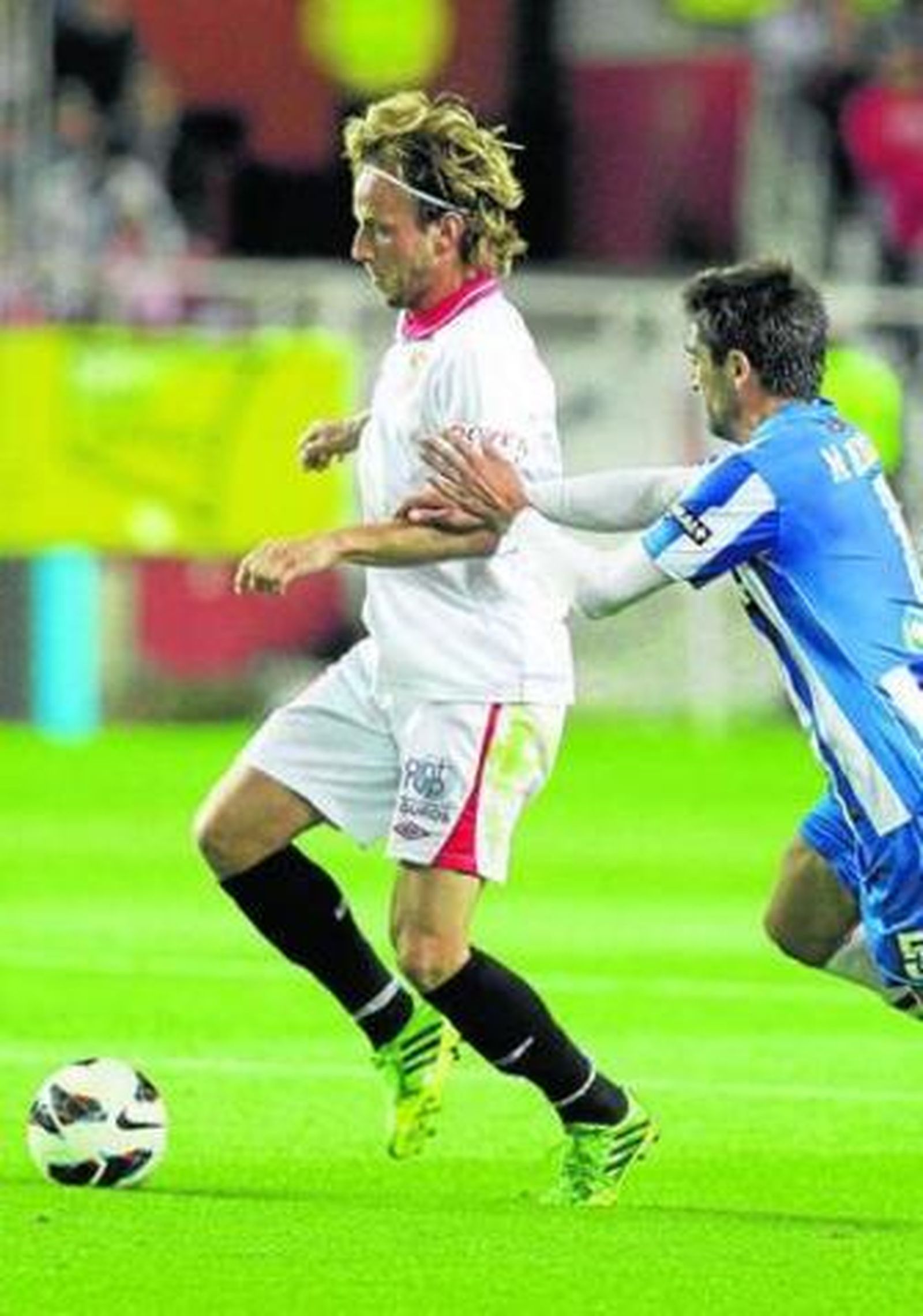 Rakitic conduce el balón perseguido por Bergara.