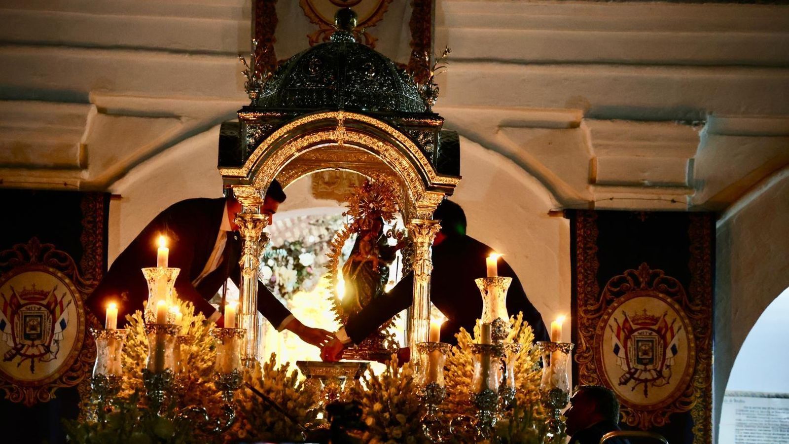 Servidores de la hermandad posan a la Virgen de la Cinta en su paso