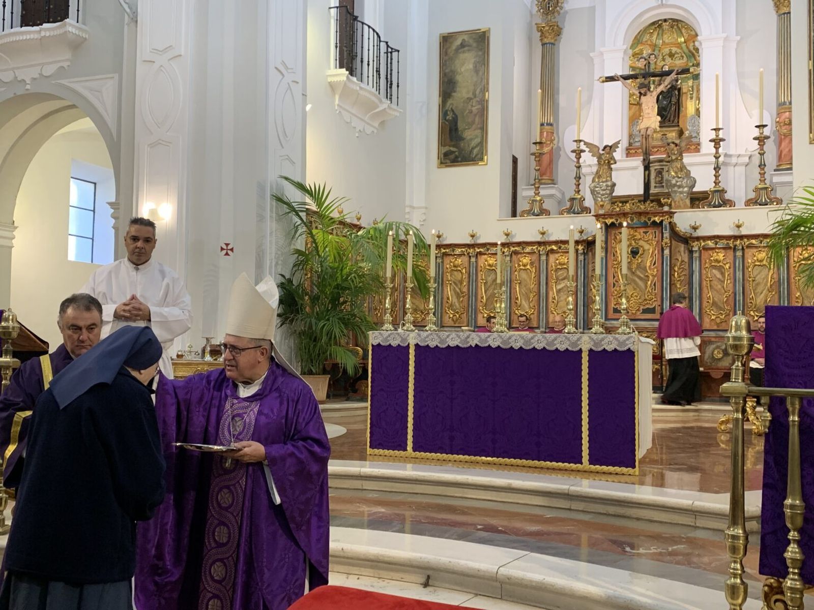 El obispo de Huelva impone la ceniza a una monja.