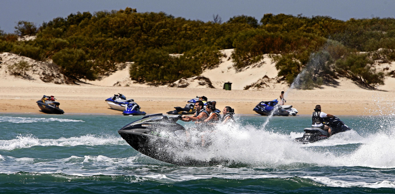Motos acuáticas en el Caño de Sancti Petri con la playa de la Punta del Boquerón al fondo, en un imagen de archivo.