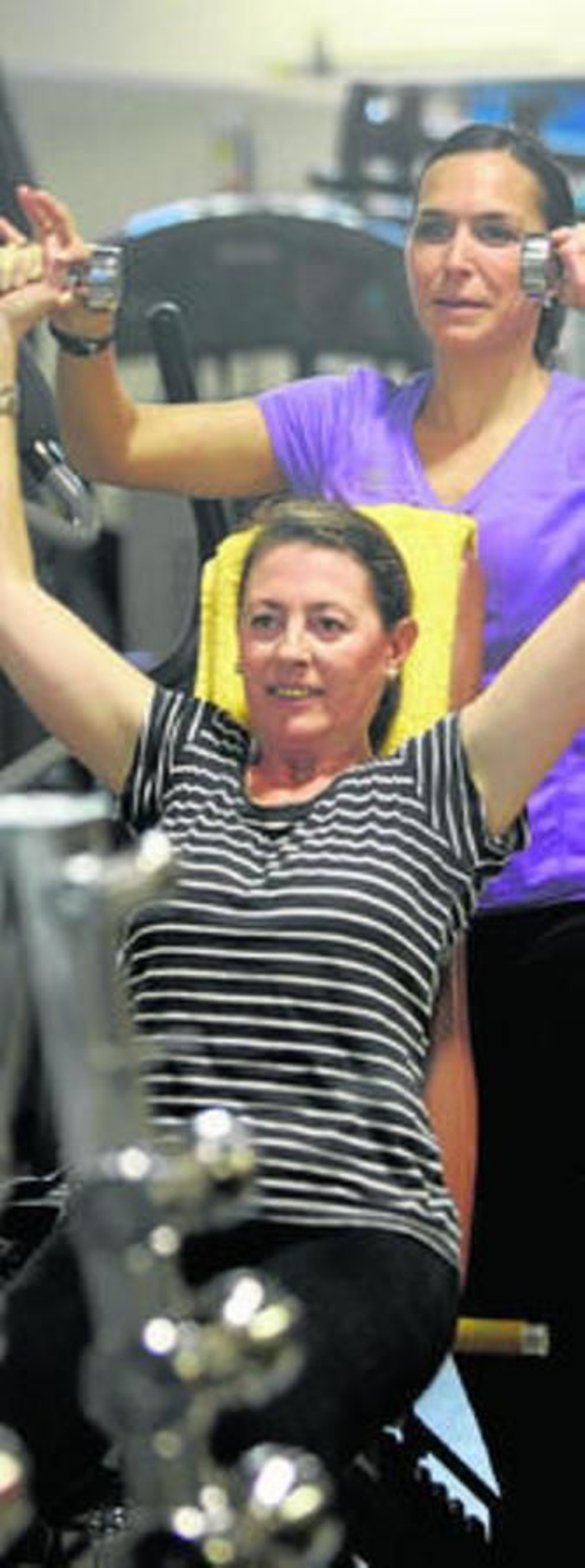 Una monitoria ayuda a una cliente en un gimnasio de Córdoba.