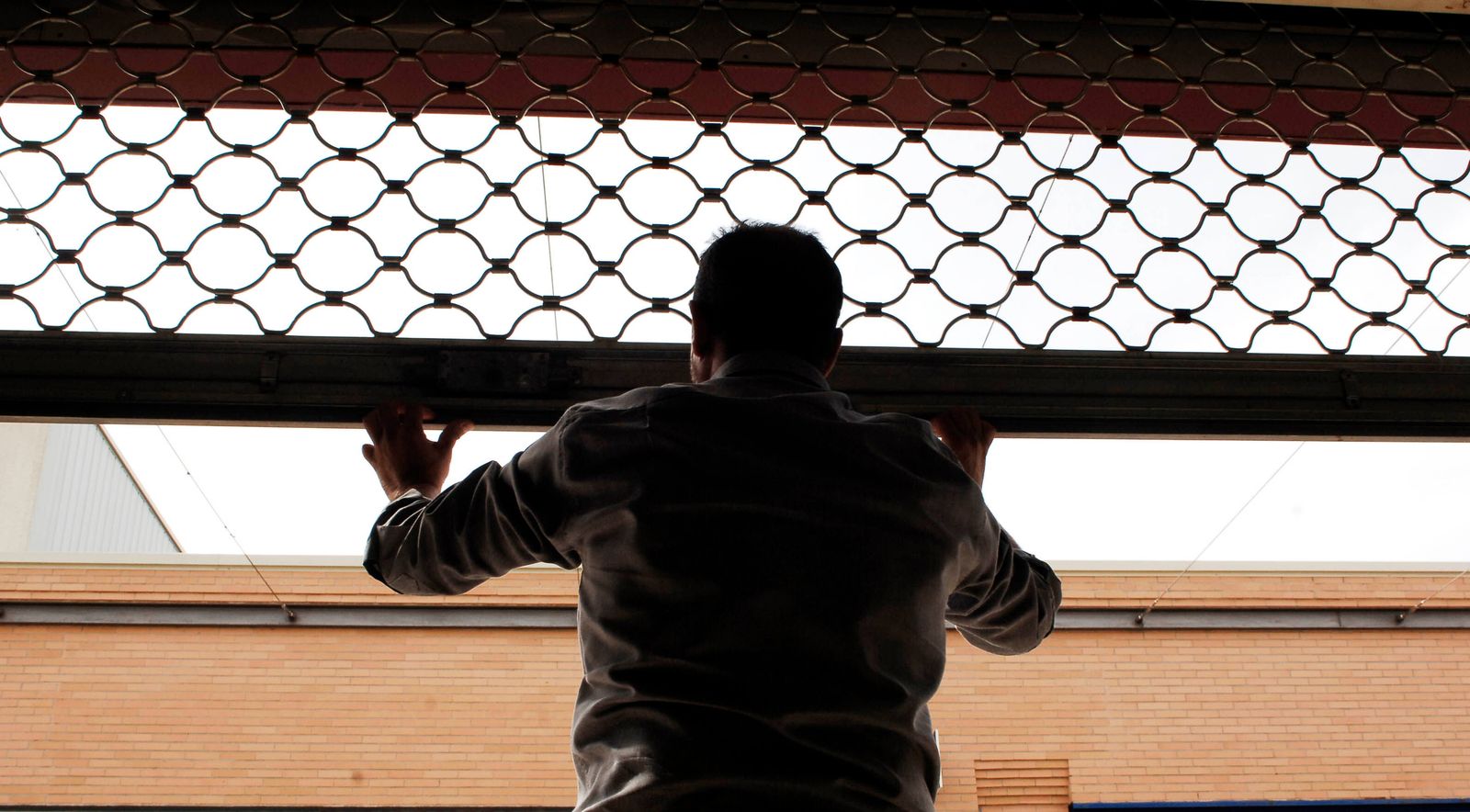 Un comerciante cierra la persiana de su negocio.