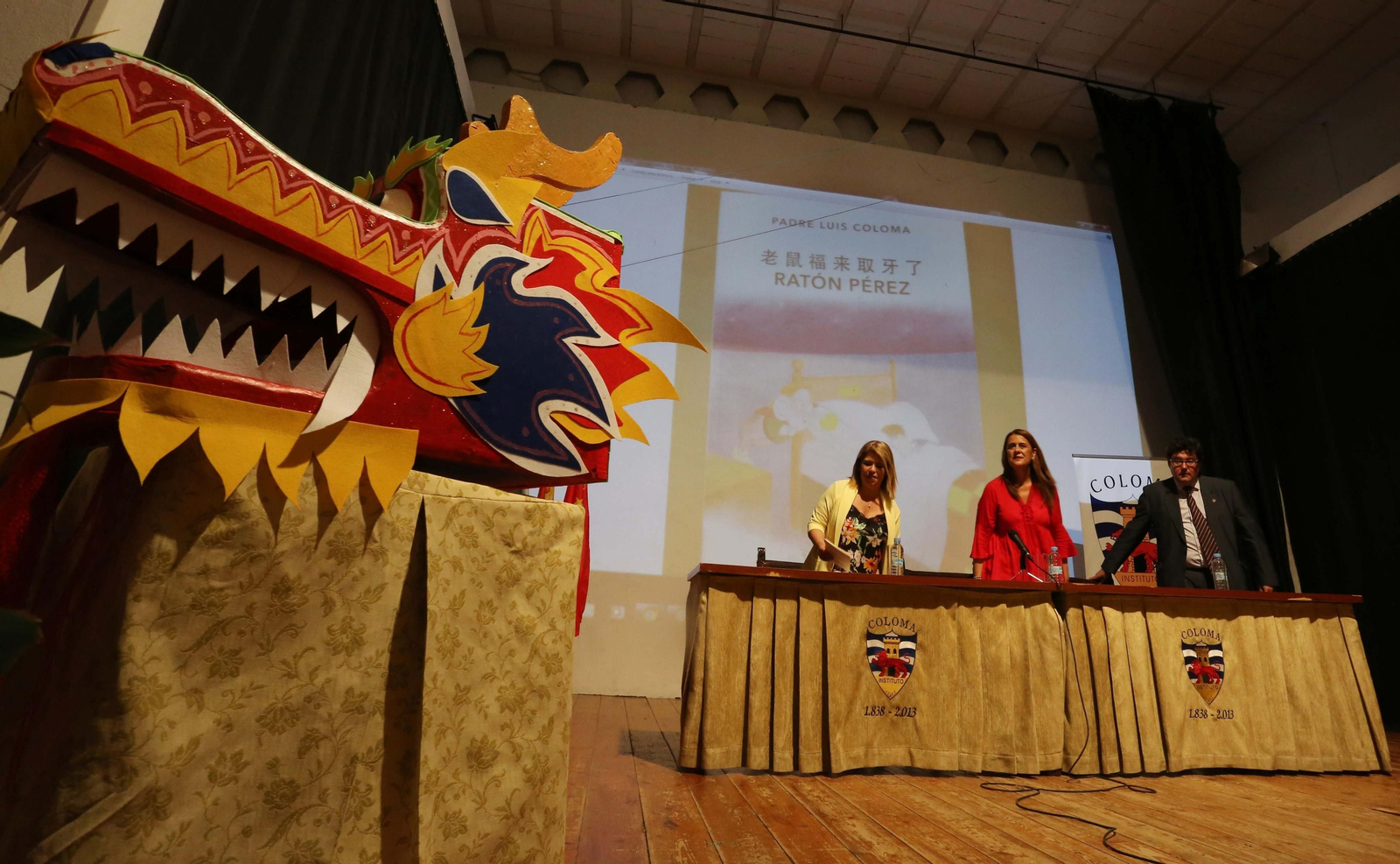 La cabeza de un dragón chino y al fondo, Mamen Sánchez, Sonia Gaya y José Ángel Aparicio.