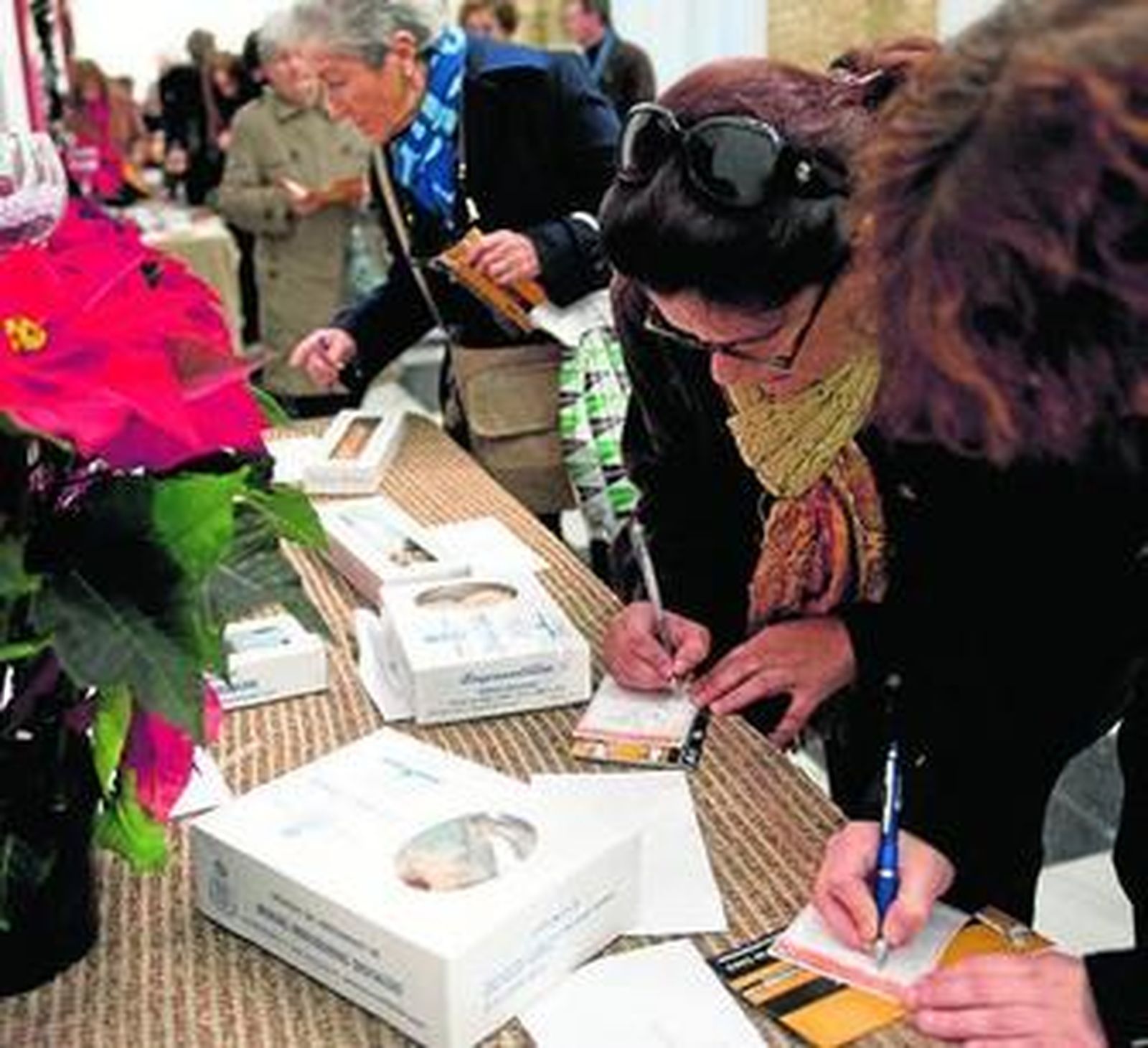 Varias personas mirando el muestrario de productos y haciendo su pedido, ayer en Diputación.