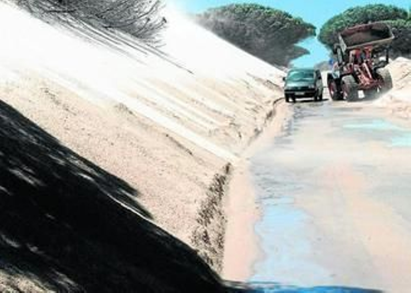Una furgoneta sale del poblado de Paloma Baja sorteando una máquina que retira arena de la duna.