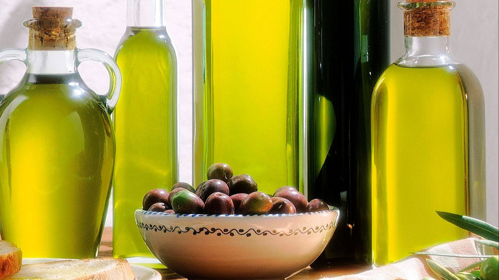 Botellas de aceite junto a unas aceitunas