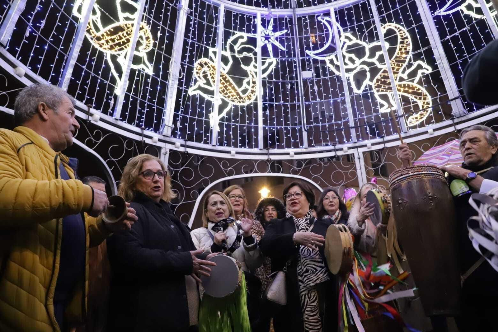 Unas mujeres cantan bajo uno de los árboles de luz de Algeciras.