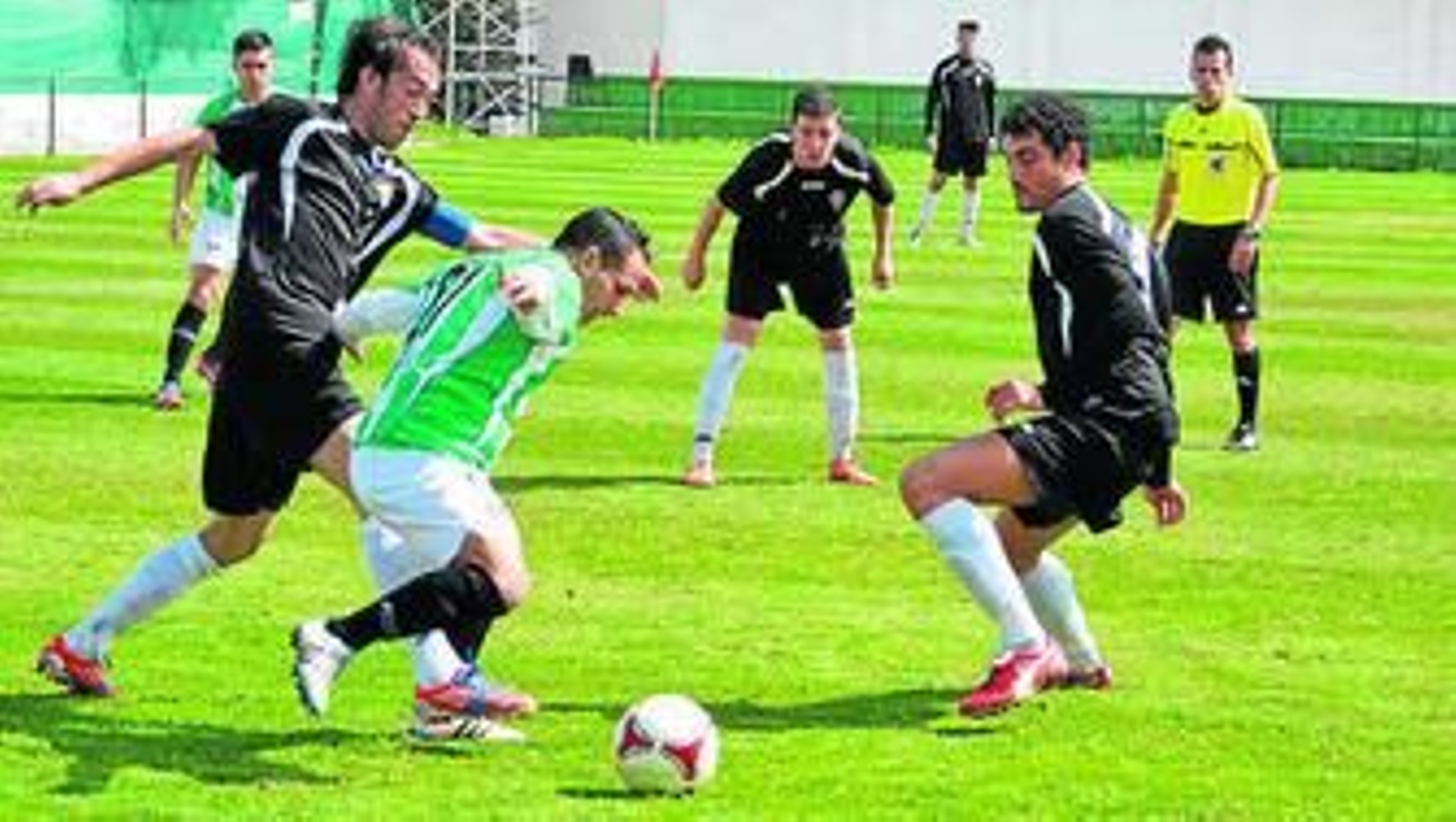 Jugadores de ambos equipos pugan por un balón.