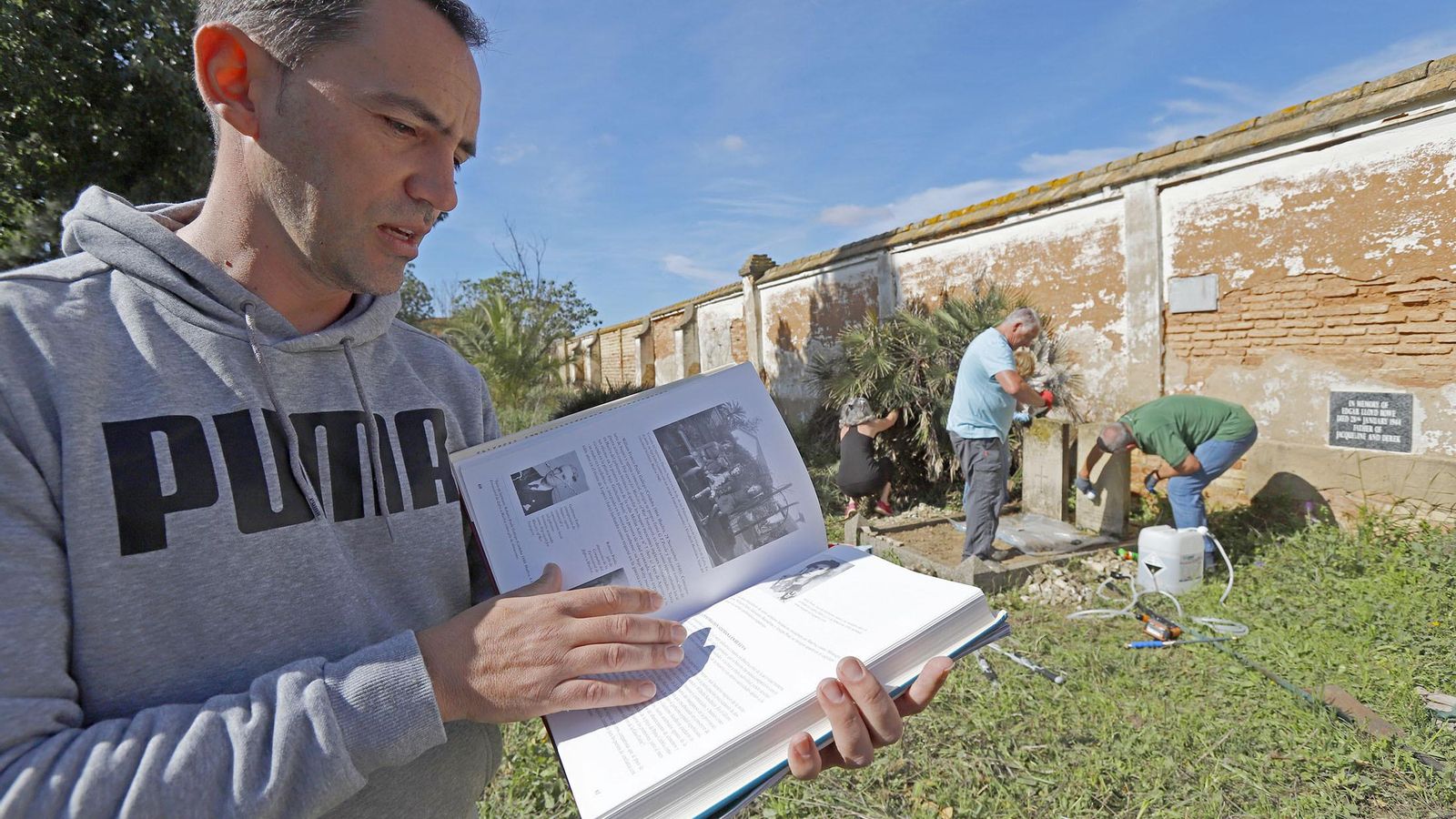 Jorge Valero muestra el libro durante la intervención en el cementerio.
