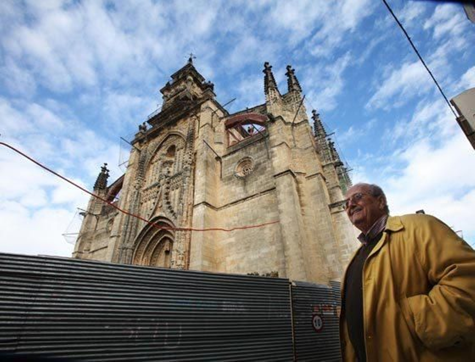 El cura de Santiago, Pedro de la Herrán, ante la parroquia y su cobertura de redes, vallas y andamios.    Foto: Vanesa Lobo