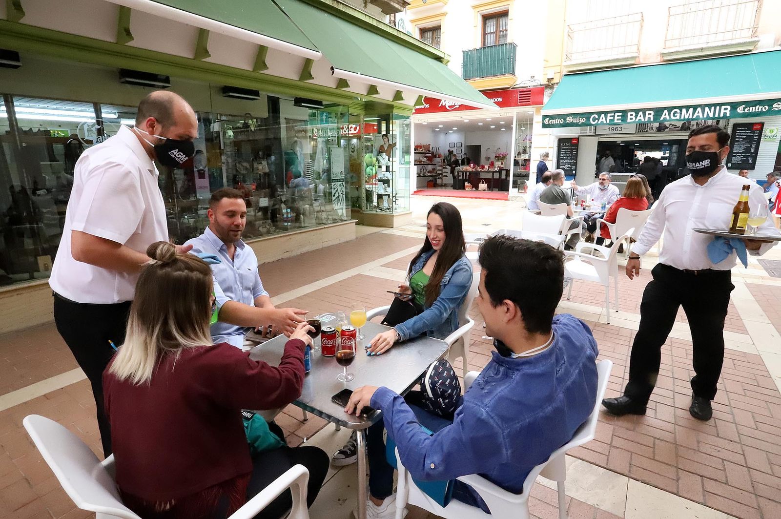 Dos camareros atienden a clientes