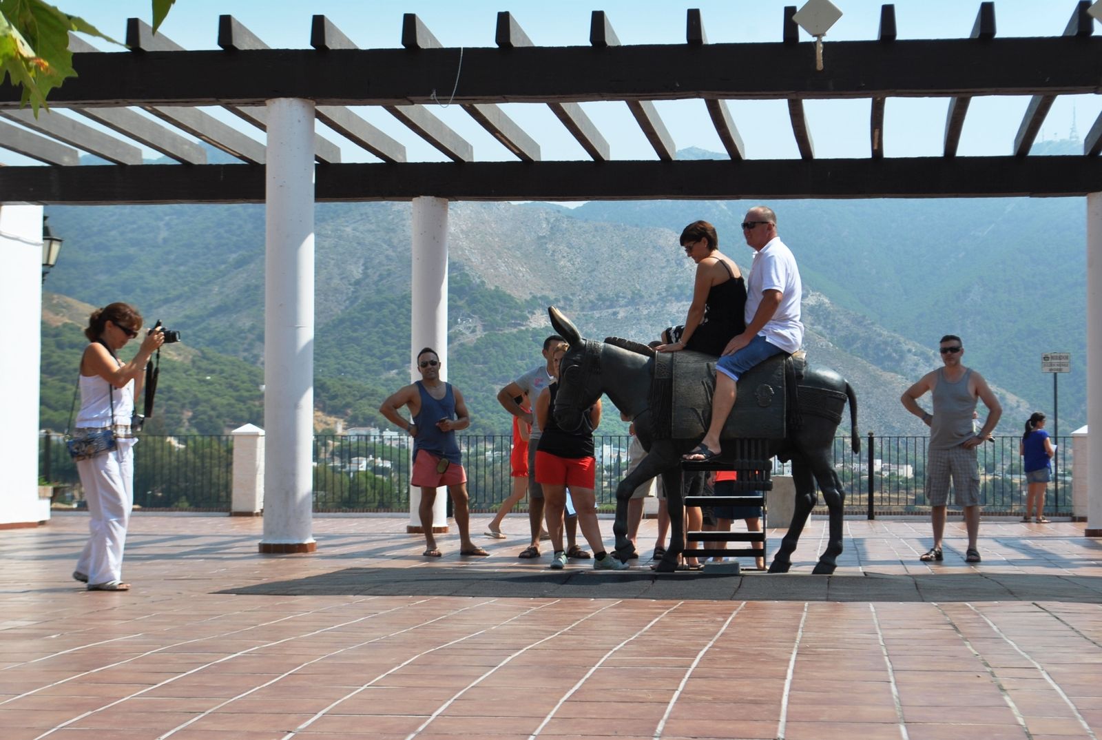 Una mujer fotografía a turistas sobre el burro de bronce en Mijas.