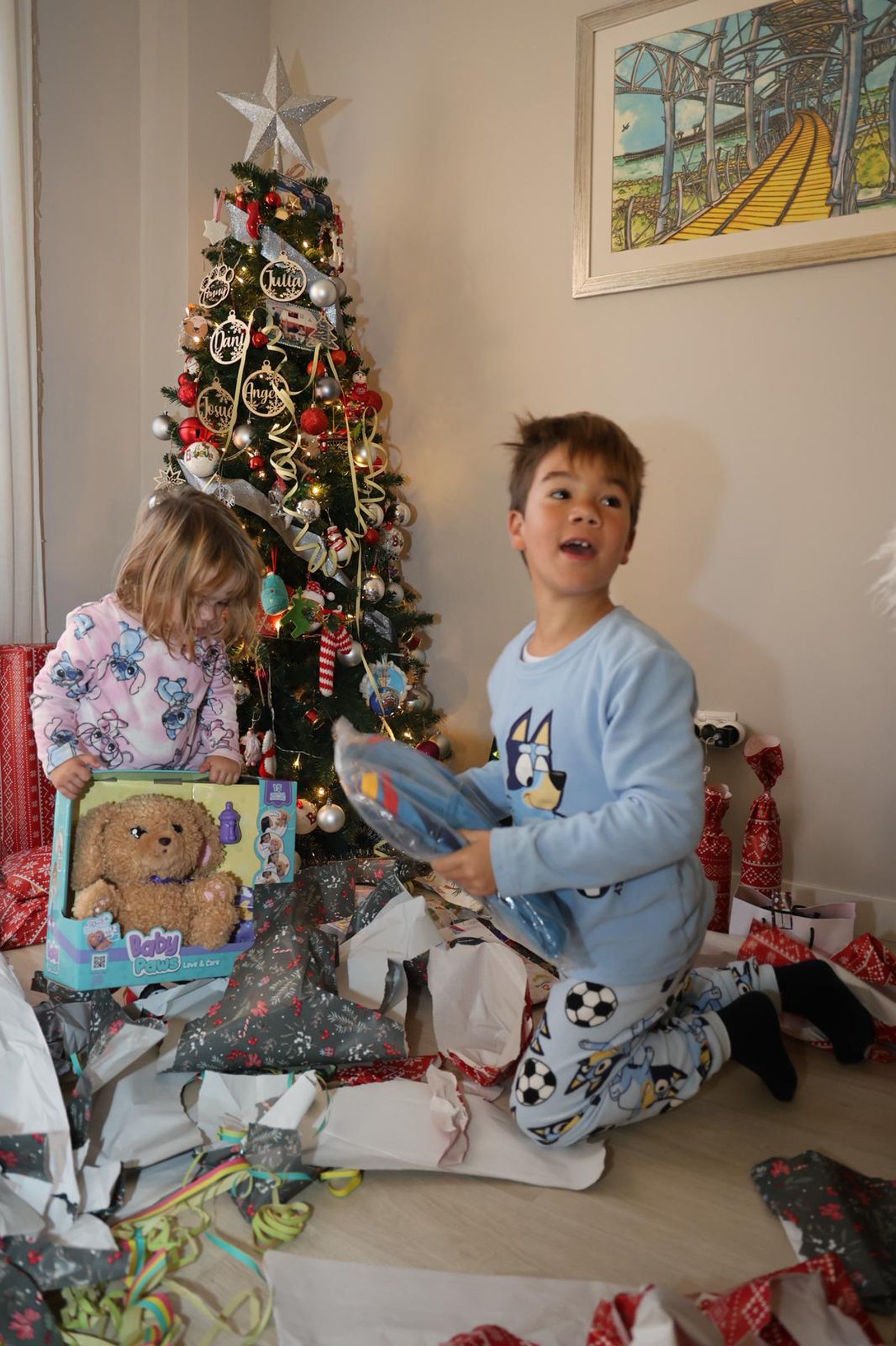 Dos niños abren sus regalos junto al árbol de Navidad este 6 de enero.