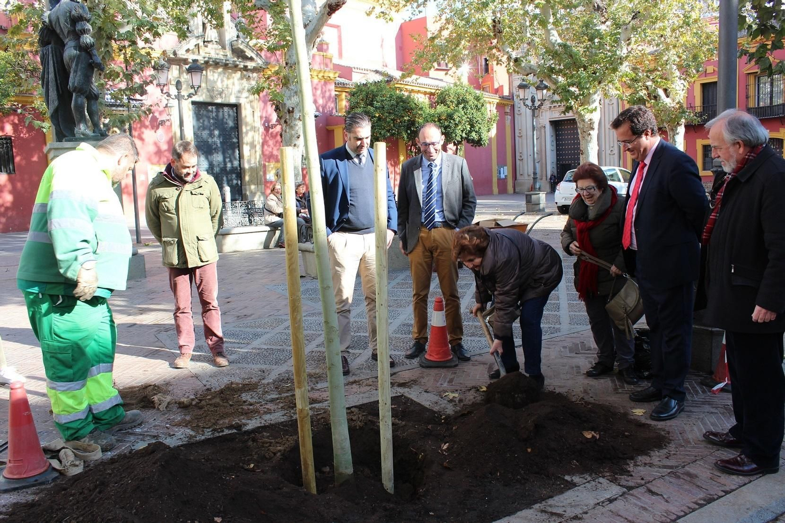 Cabrera mira como dos mujeres echan tierra a los nuevos árboles.