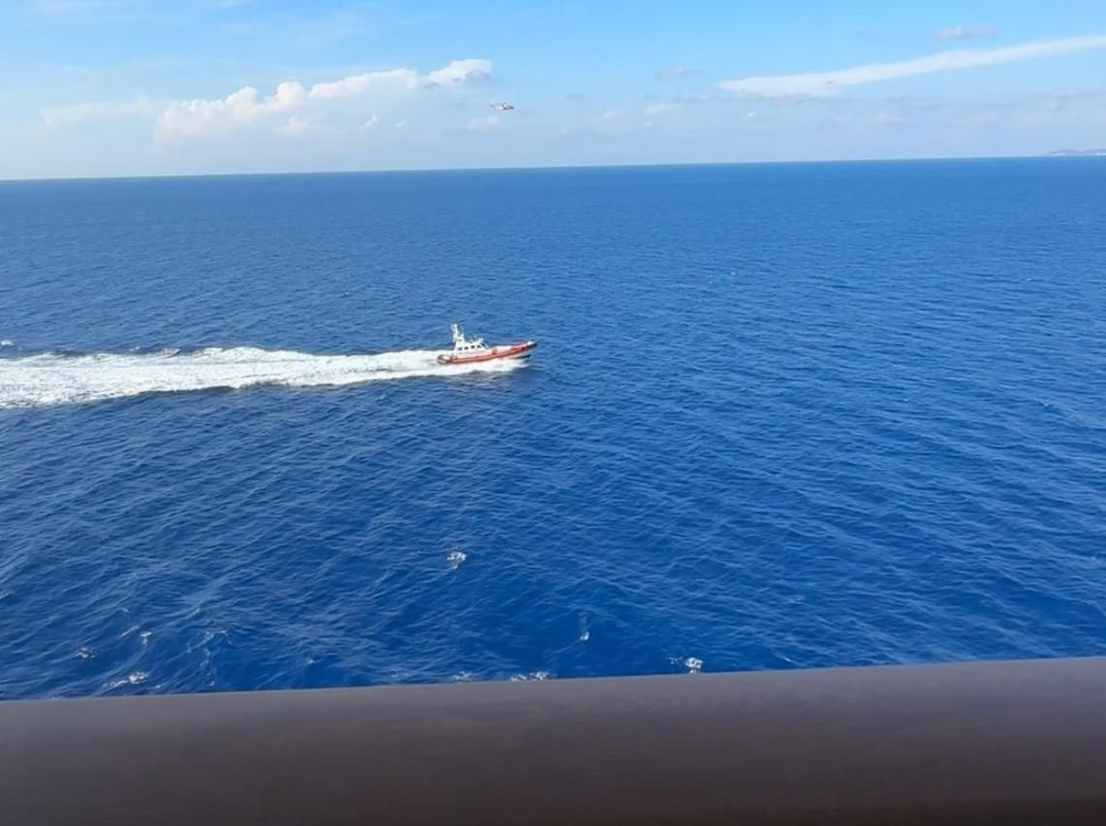 Un helicóptero y una embarcación de la guardia costera italiana vistos desde el 'MSC World Europa'.