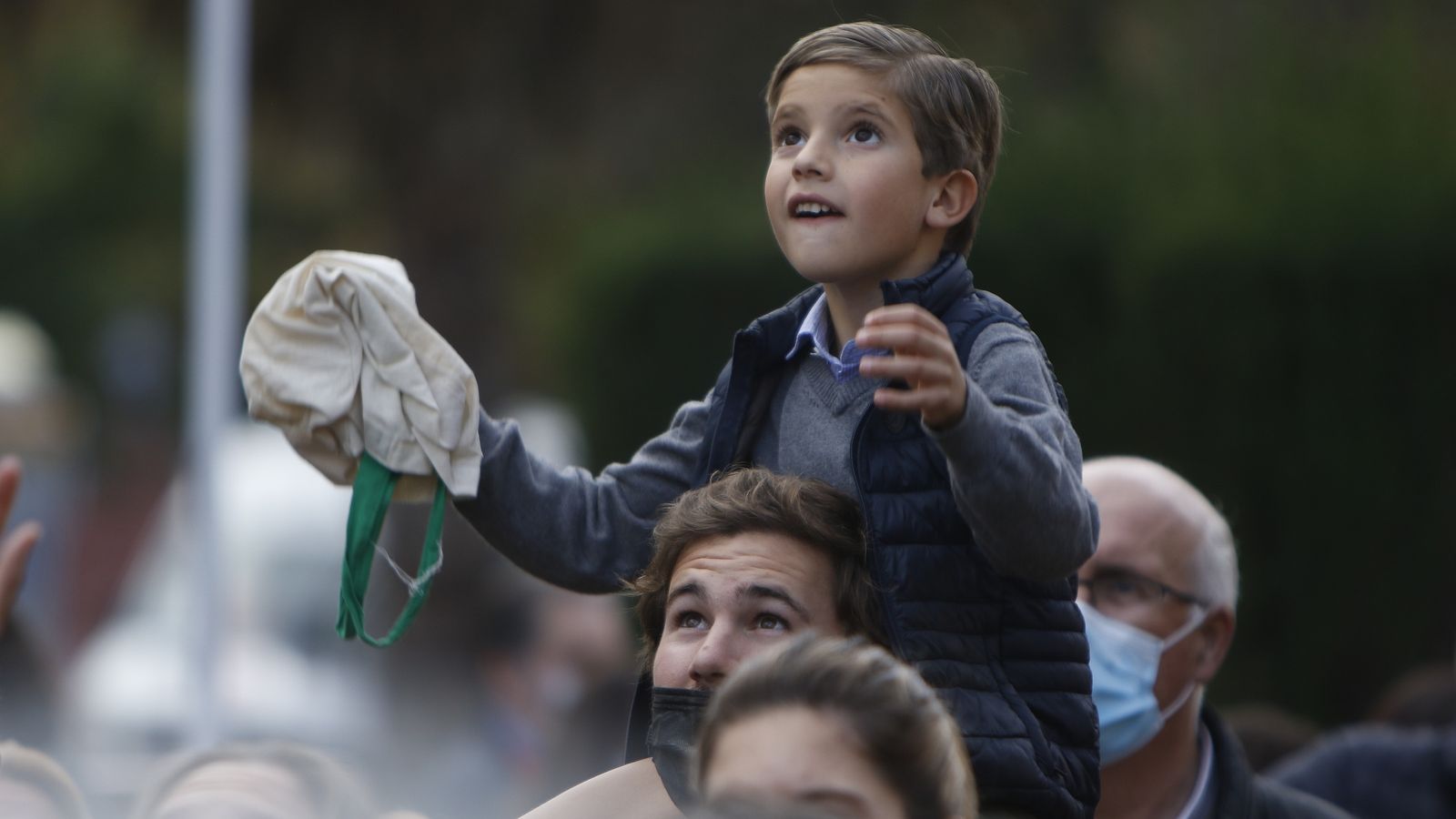 Un niño a hombros de su padre espera la llegada de los caramelos.