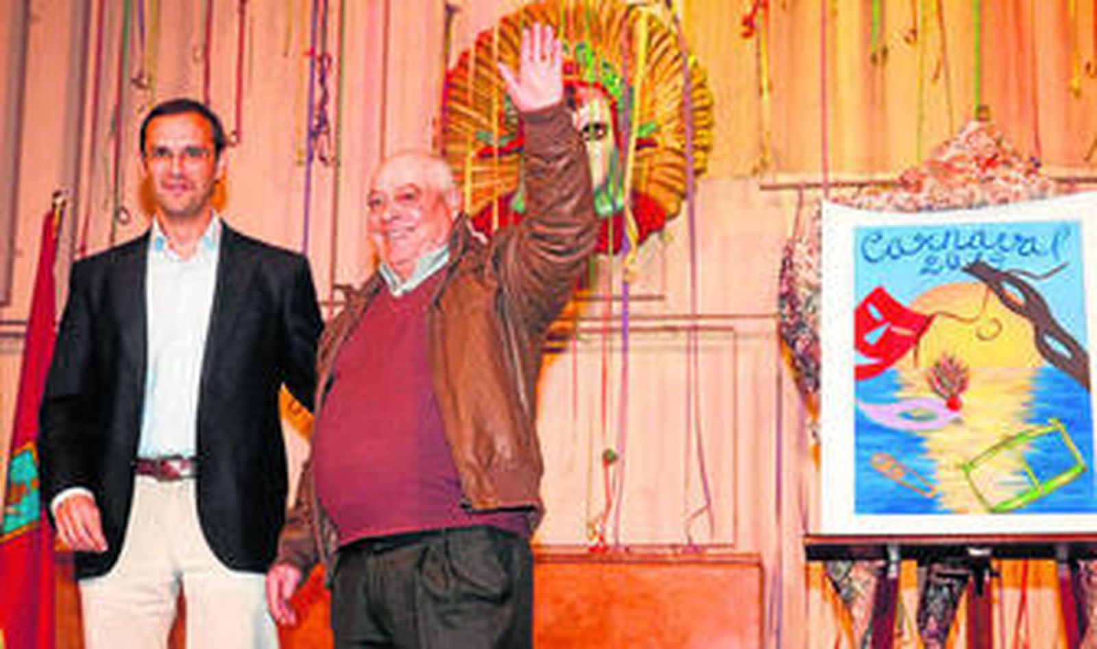 El concejal Víctor Mora con el carnavalero Manuel García, que recibió la Máscara de Oro junto al cartel anunciador.