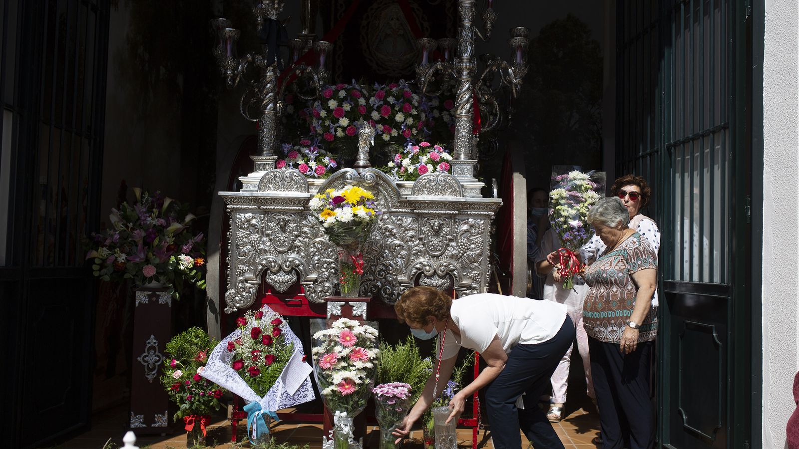 Varias manriqueñas depositan flores delante de la carreta que porta el Simpecado que recibe a las hermandades.