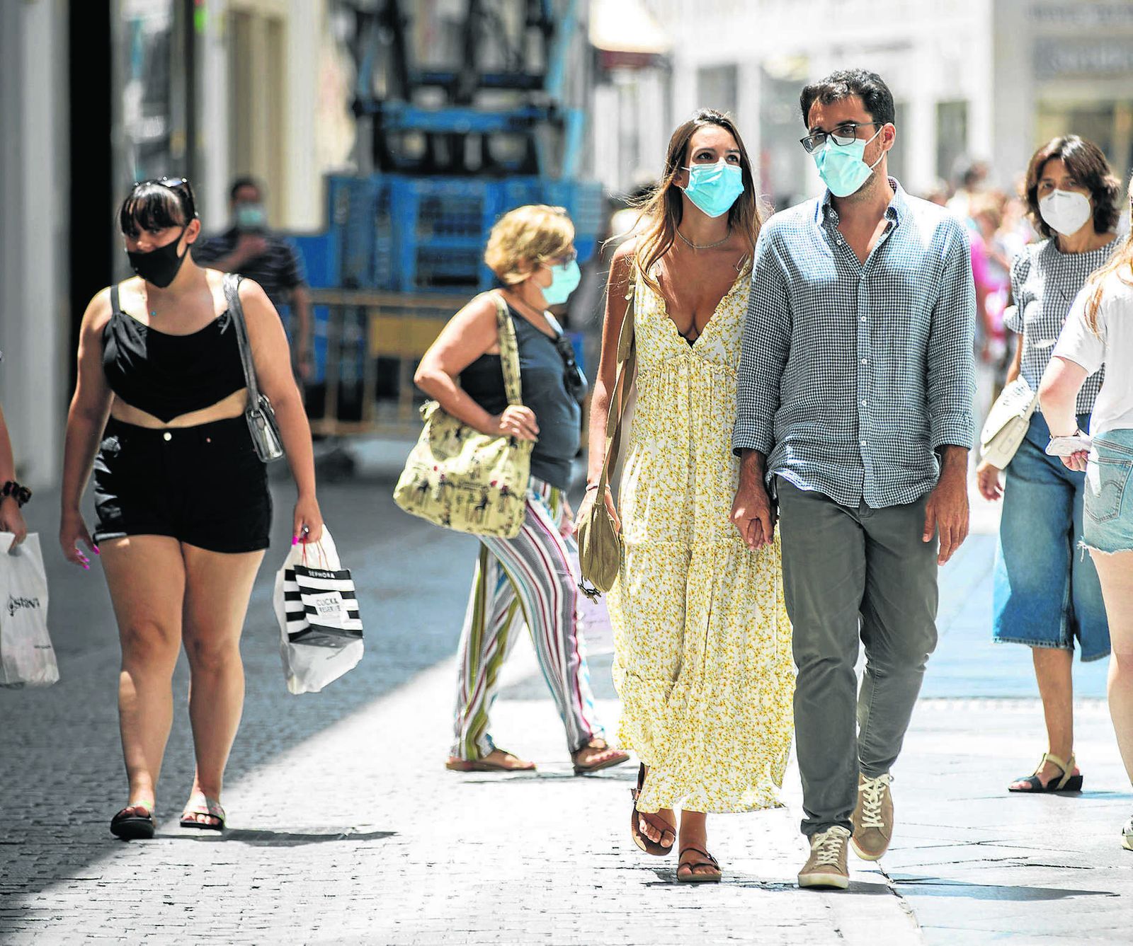 Personas caminan por el centro de Sevilla provistas de la obligatoria mascarilla.