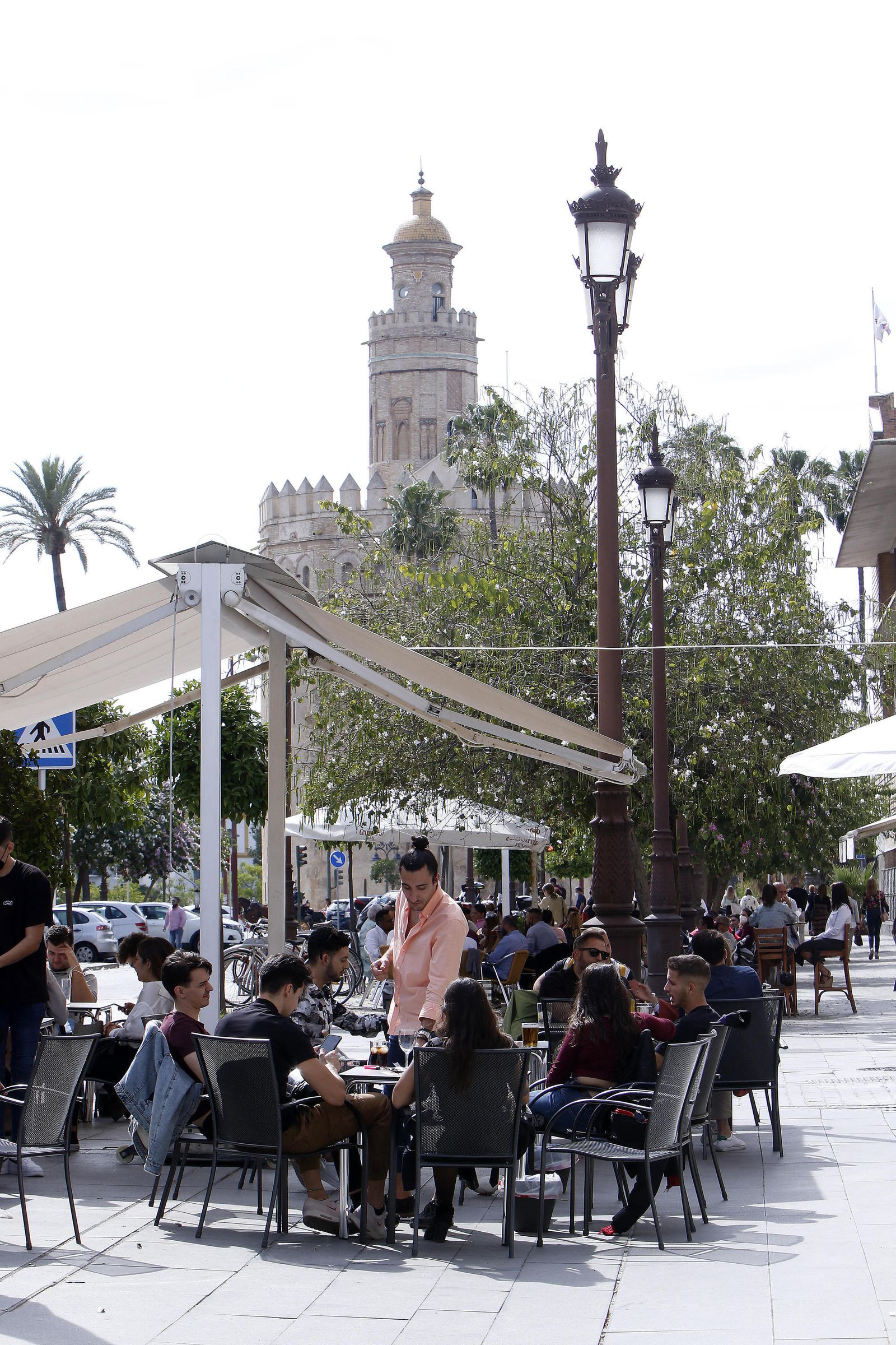 La terraza de un bar junto a la Torre del Oro, repleta de clientes.