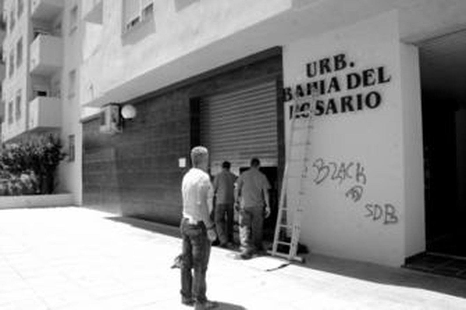 Operarios reponen la puerta de Caprichos Di-vinos, ayer, en la urbanización Bahía del Rosario.