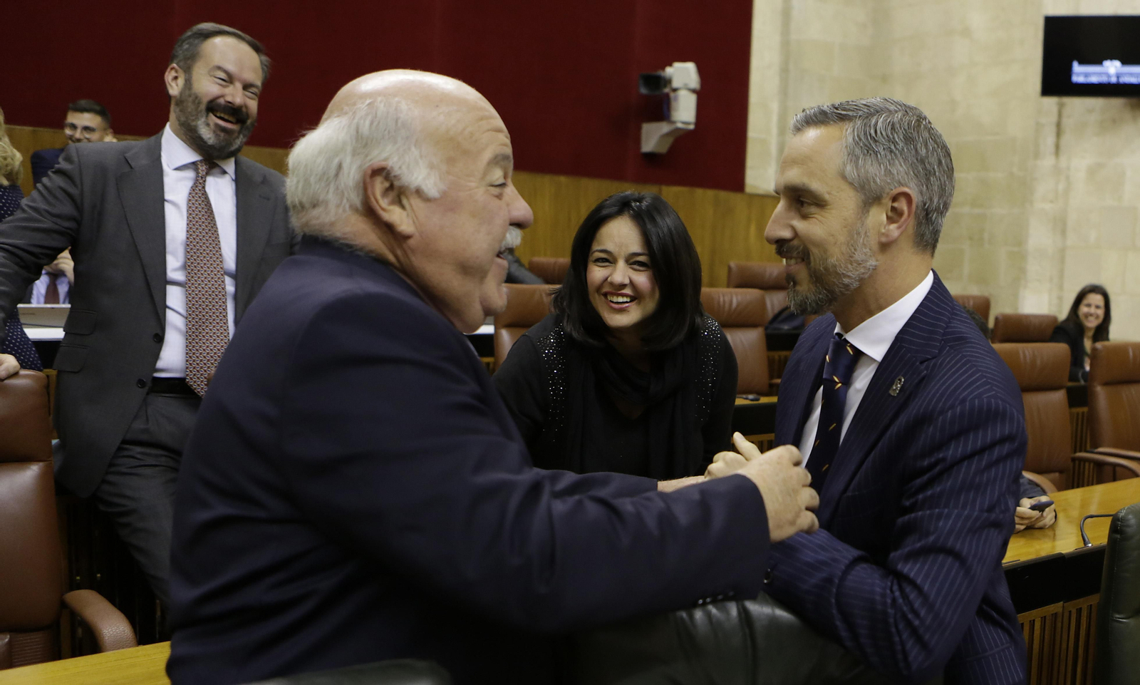 El consejero de Salud, Jesús Aguire, saluda al titular de Hacienda, Juan Bravo, en el Parlamento.