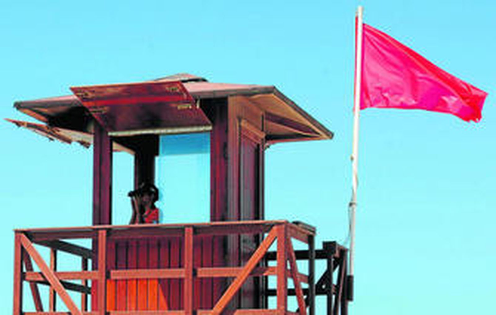 La bandera roja ondeando en una torre de vigilancia de la playa de Camposoto.