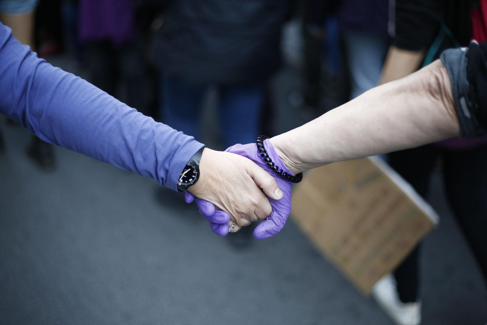 Dos mujeres se dan la mano en una manifestación por el 8M.