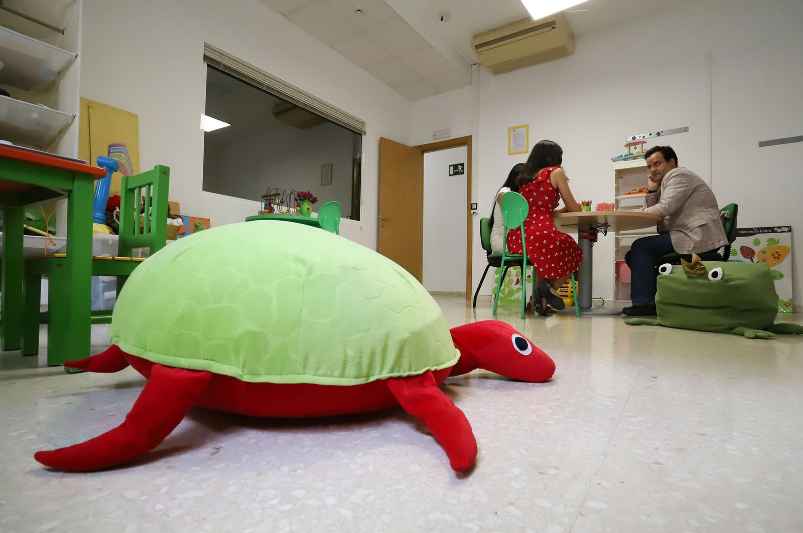 Fernando Moreno habla con otras dos profesionales del equipo en la sala de intervención, llena de juguetes para los niños.
