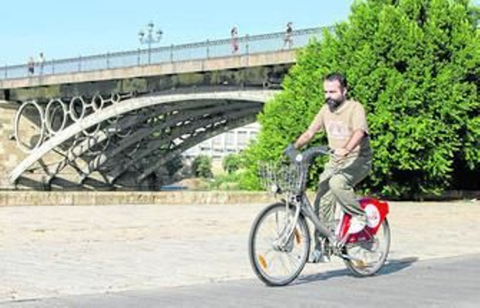 Un usuario del servicio de alquiler Sevici circula por el paseo del río