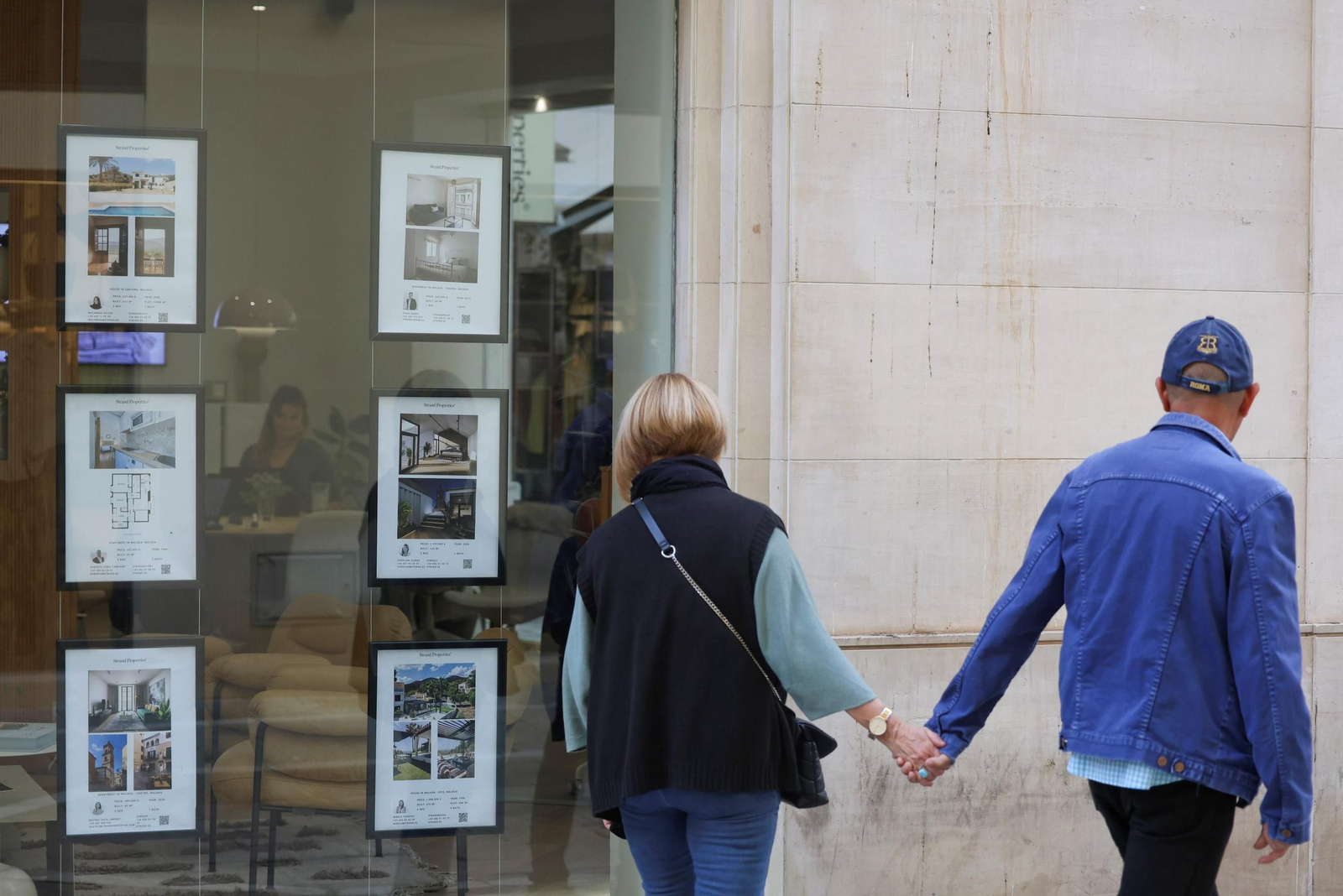 Una pareja pasa ante el escaparate de una inmobiliaria.