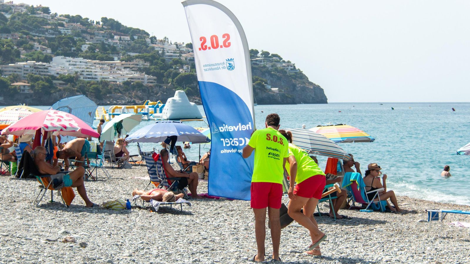 Dos socorristas colocan la banderola del puesto de auxilio en La Herradura