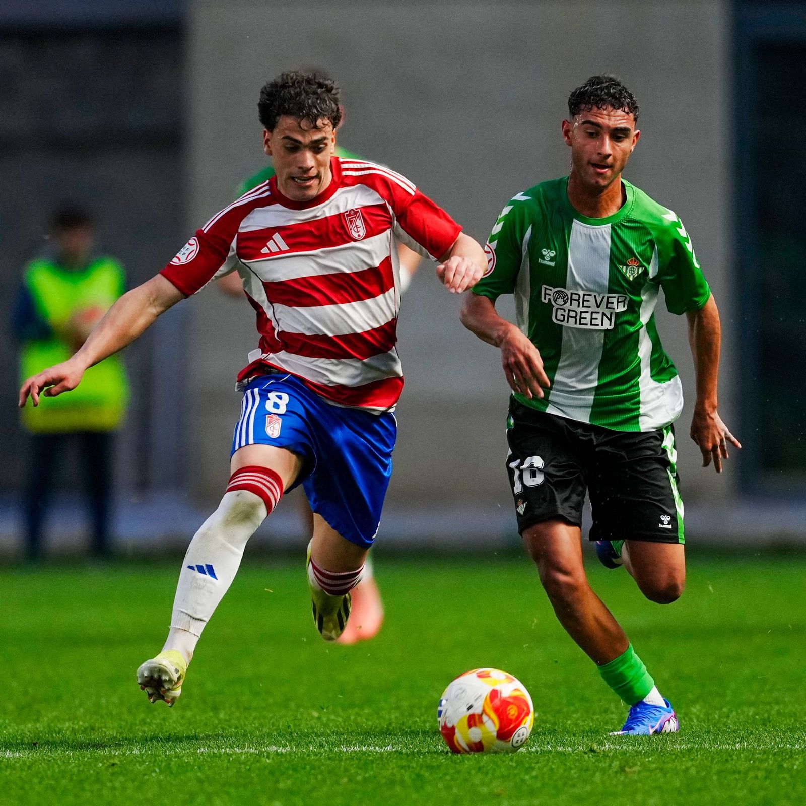 Un jugador de cada equipo corriendo tras el balón.