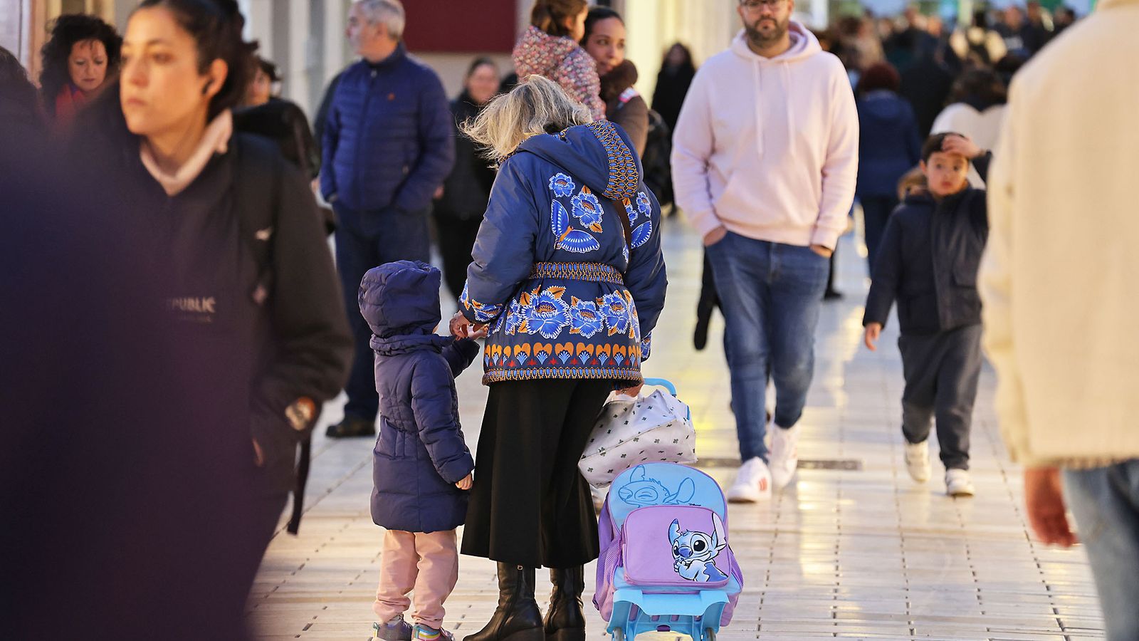 Una mujer acompaña a una niña por las calles llenas de gente de Huelva.
