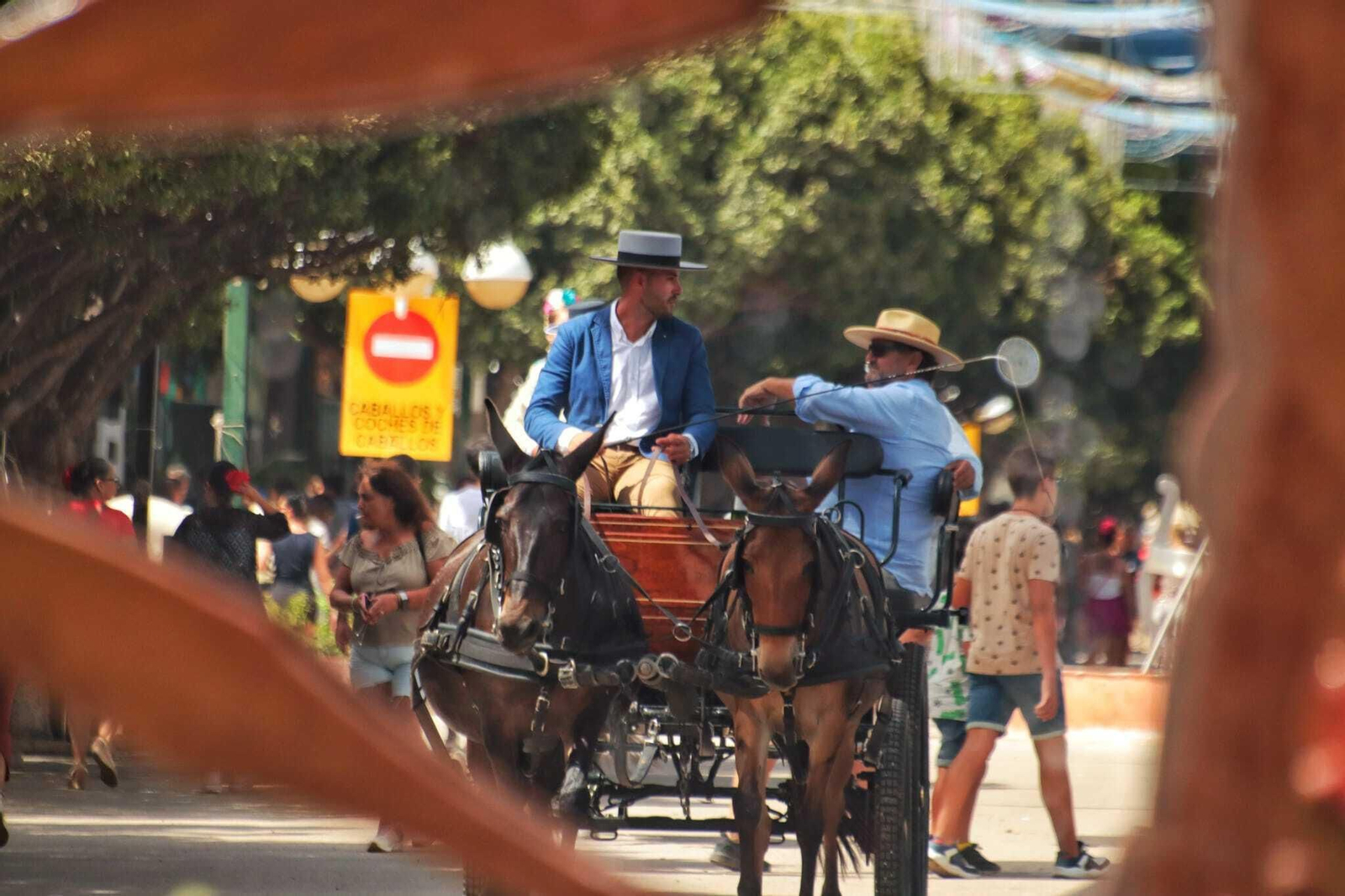 Dos hombres montan un coche de caballos en el Real.