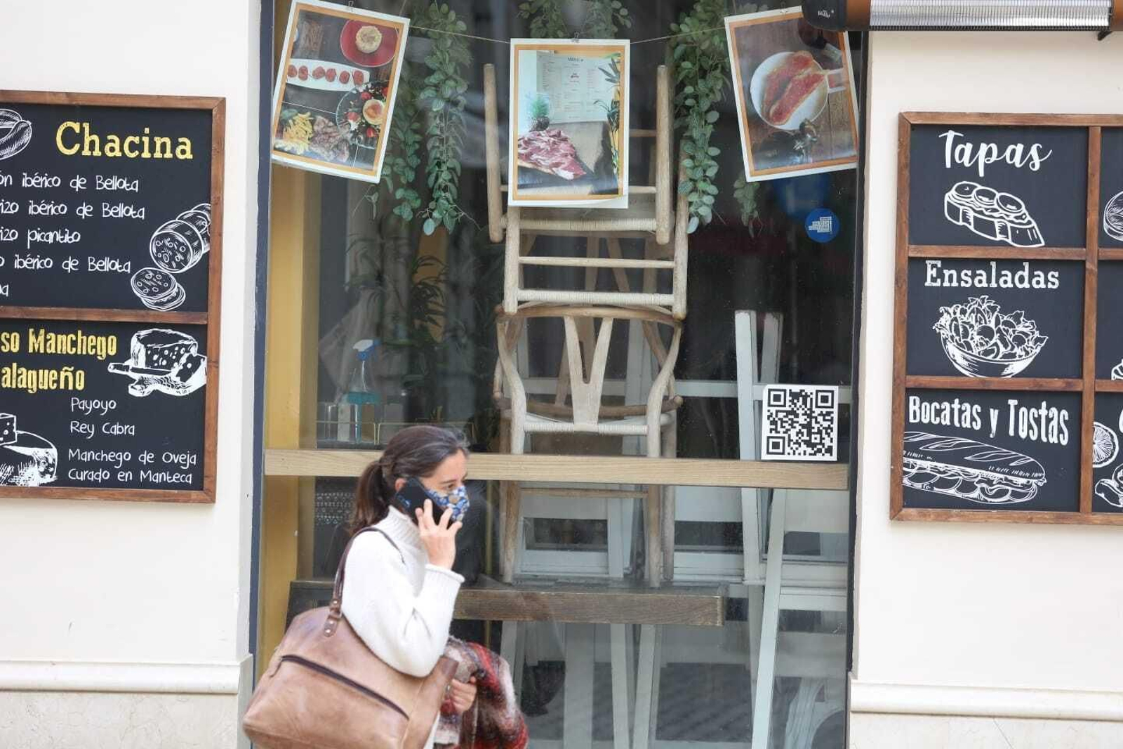 Una mujer pasea junto a un restaurante de Málaga cerrado