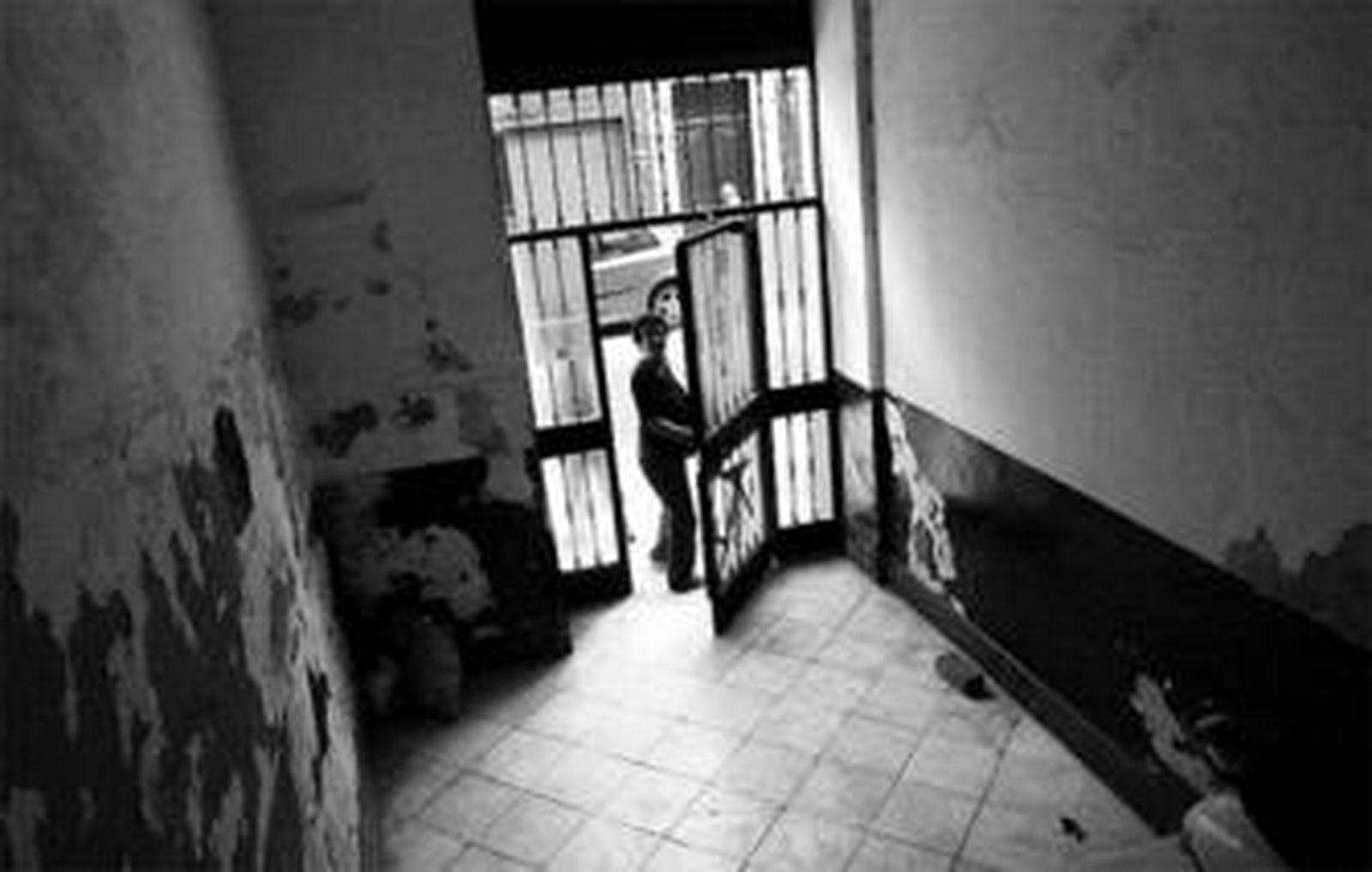 Una vecina sale de un bloque cuyo portal se encuentra en muy mal estado.