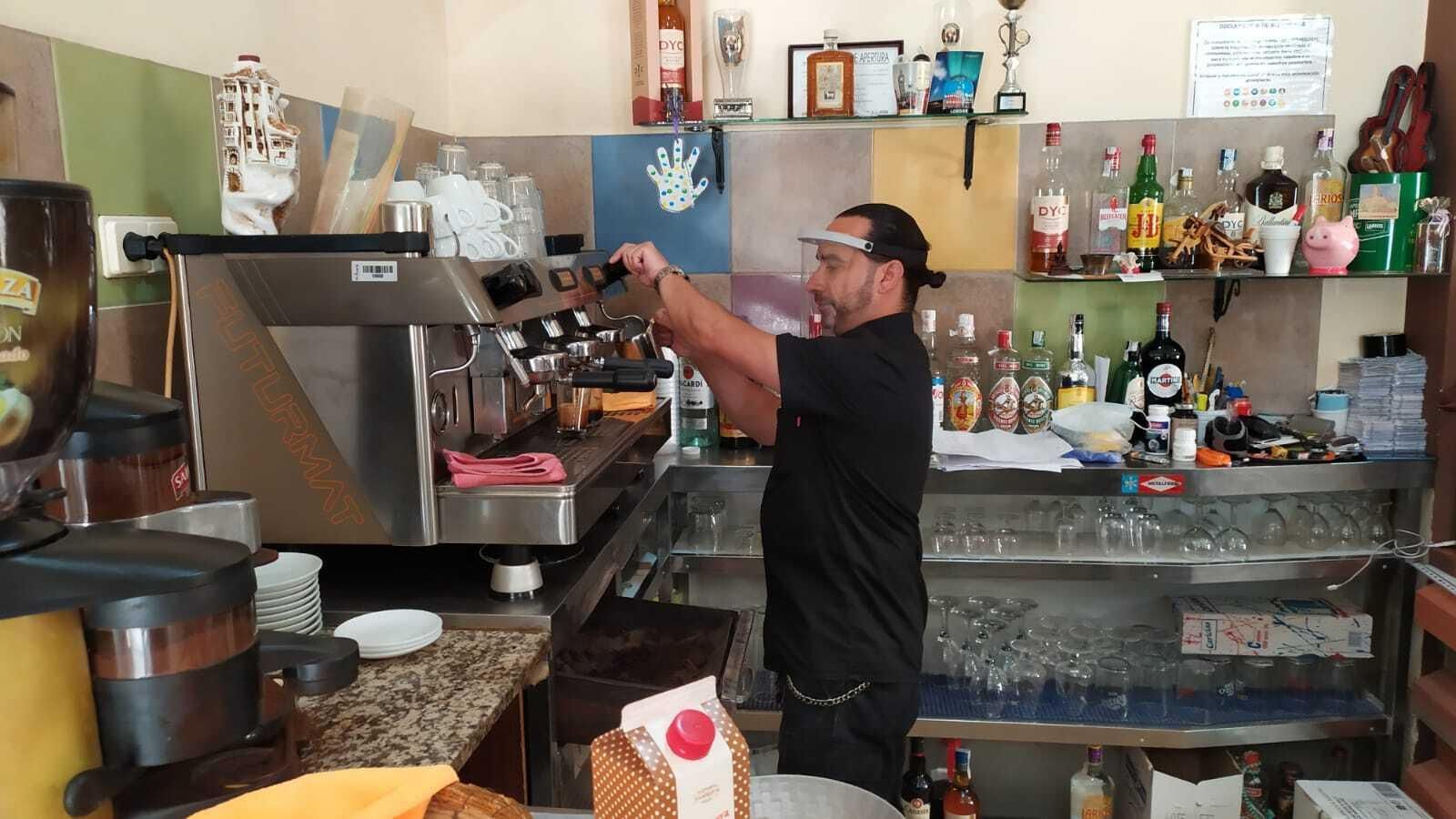 Un camarero prepara un café pertrechado con una pantalla facial, este lunes.
