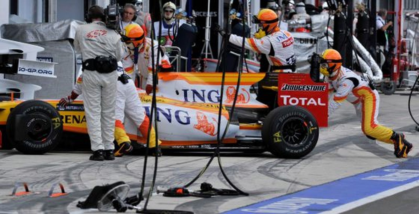 Los mecánicos de Renault retiran el coche del piloto español Fernando Alonso, después de que perdiera una rueda.  Foto: Efe