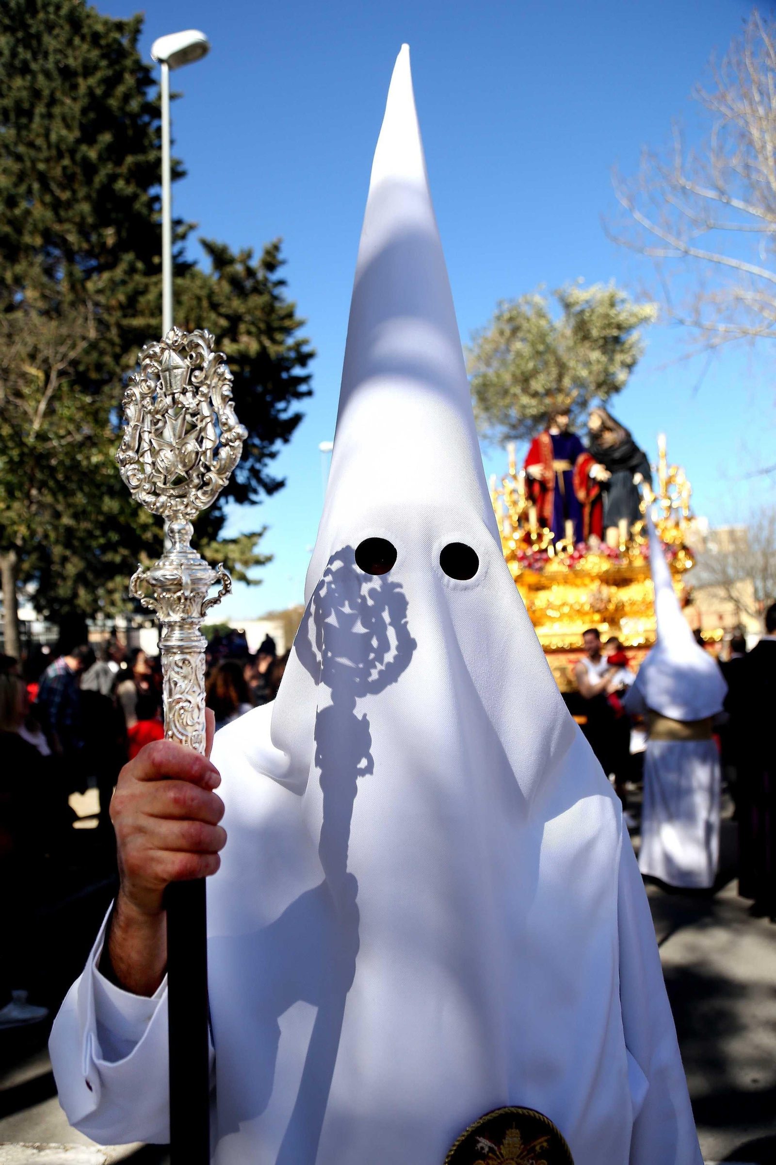 Un penitente de la presidencia del misterio. Tras él, el paso del Señor de la Clemencia.