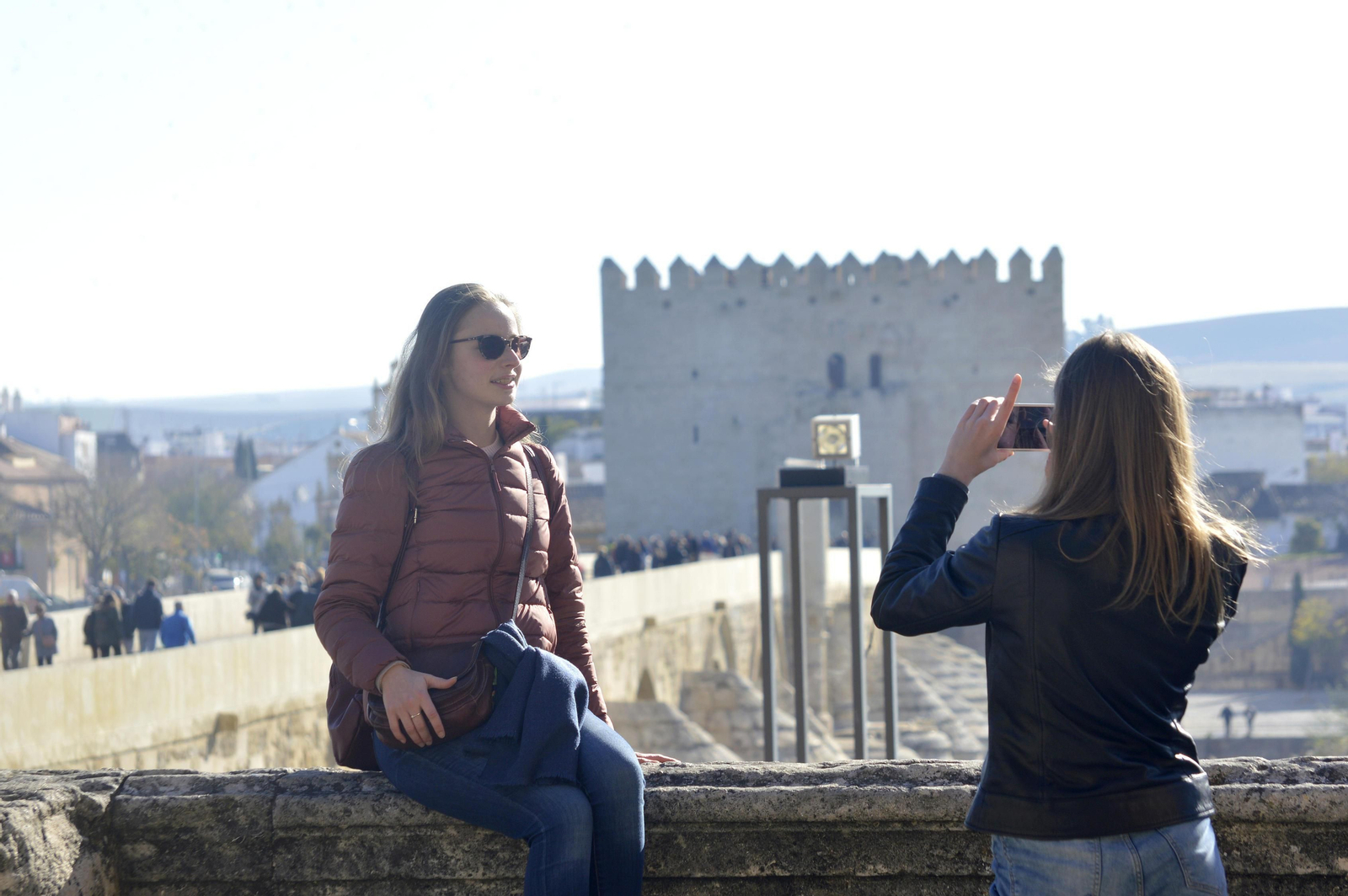 Una turista le toma una fotografía a otra con el puente romano y la torre de la Calahorra a sus espaldas.